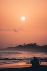 A couple of people sitting on top of a sandy beach