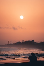 A couple of people sitting on top of a sandy beach
