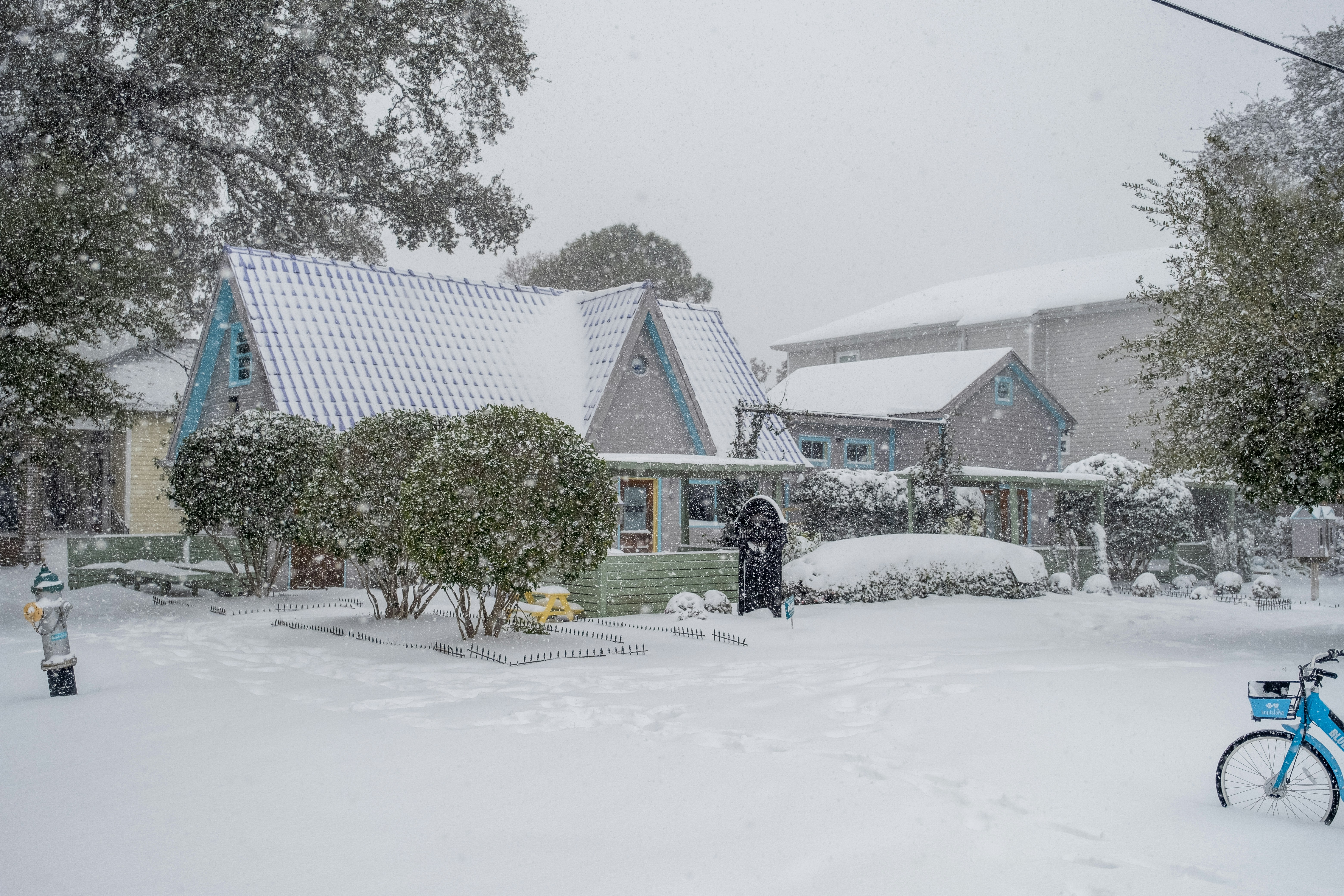 A bicycle is parked in the snow in front of a house