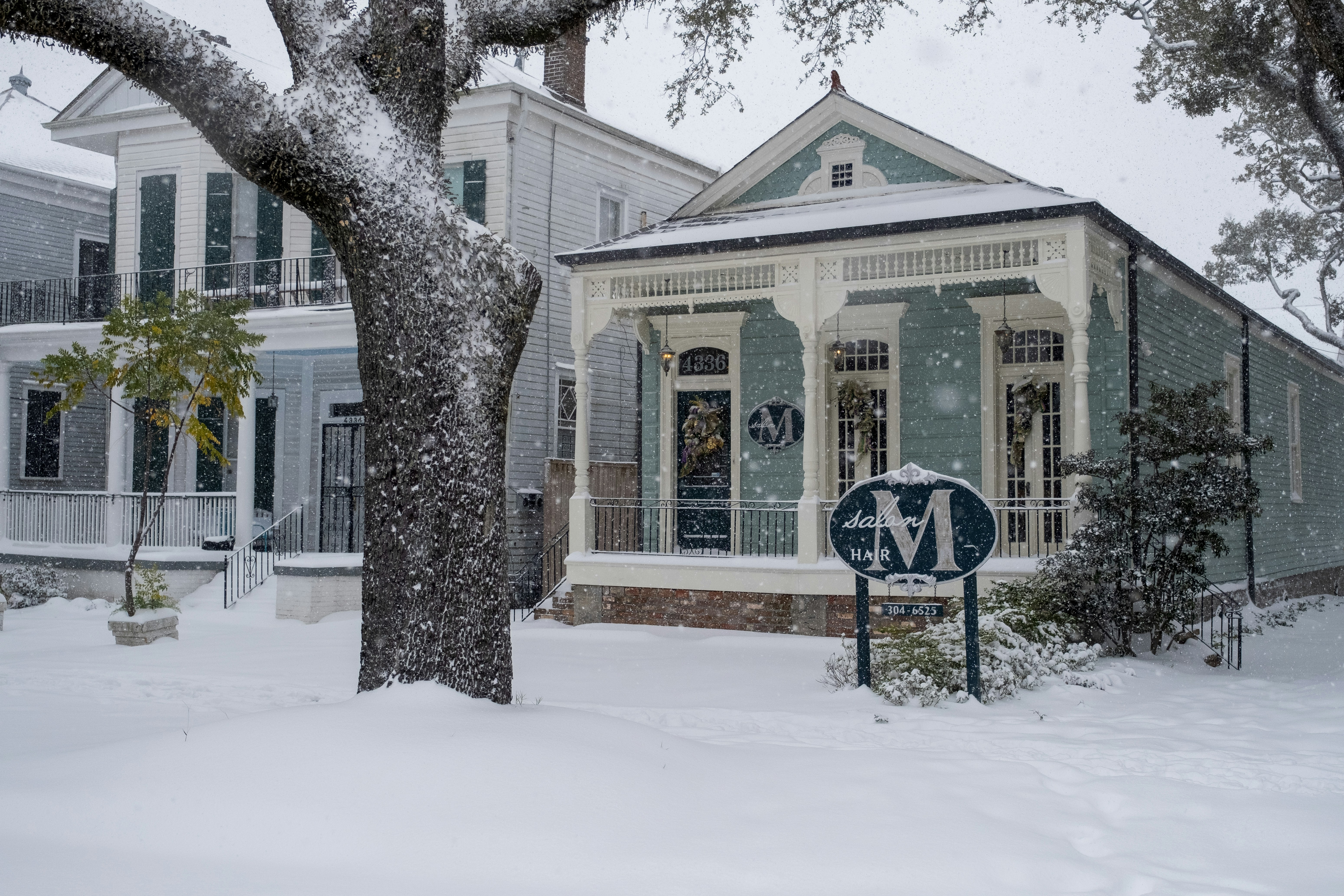 A snow covered street with a house and trees