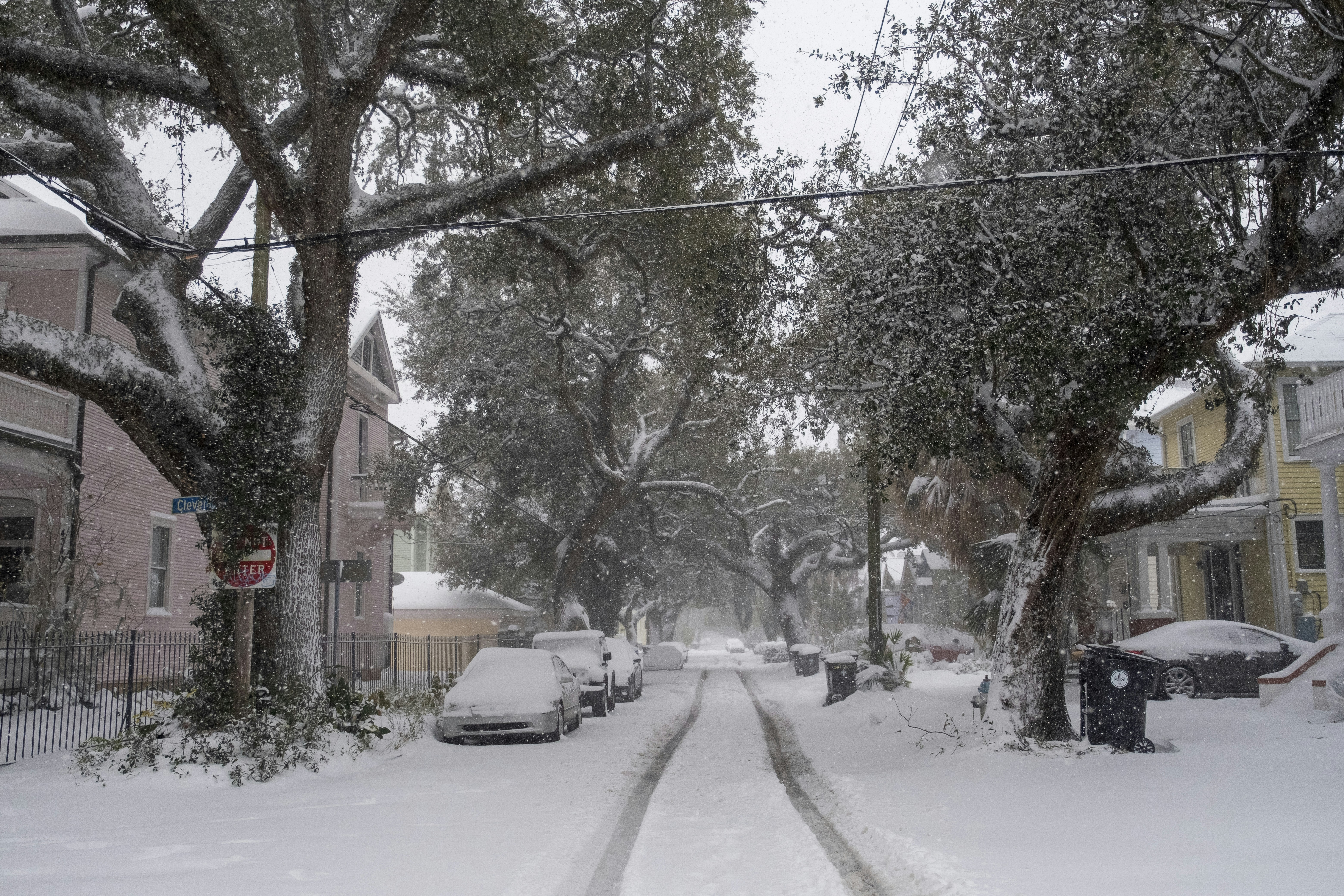 A snow covered street with cars parked on the side of it