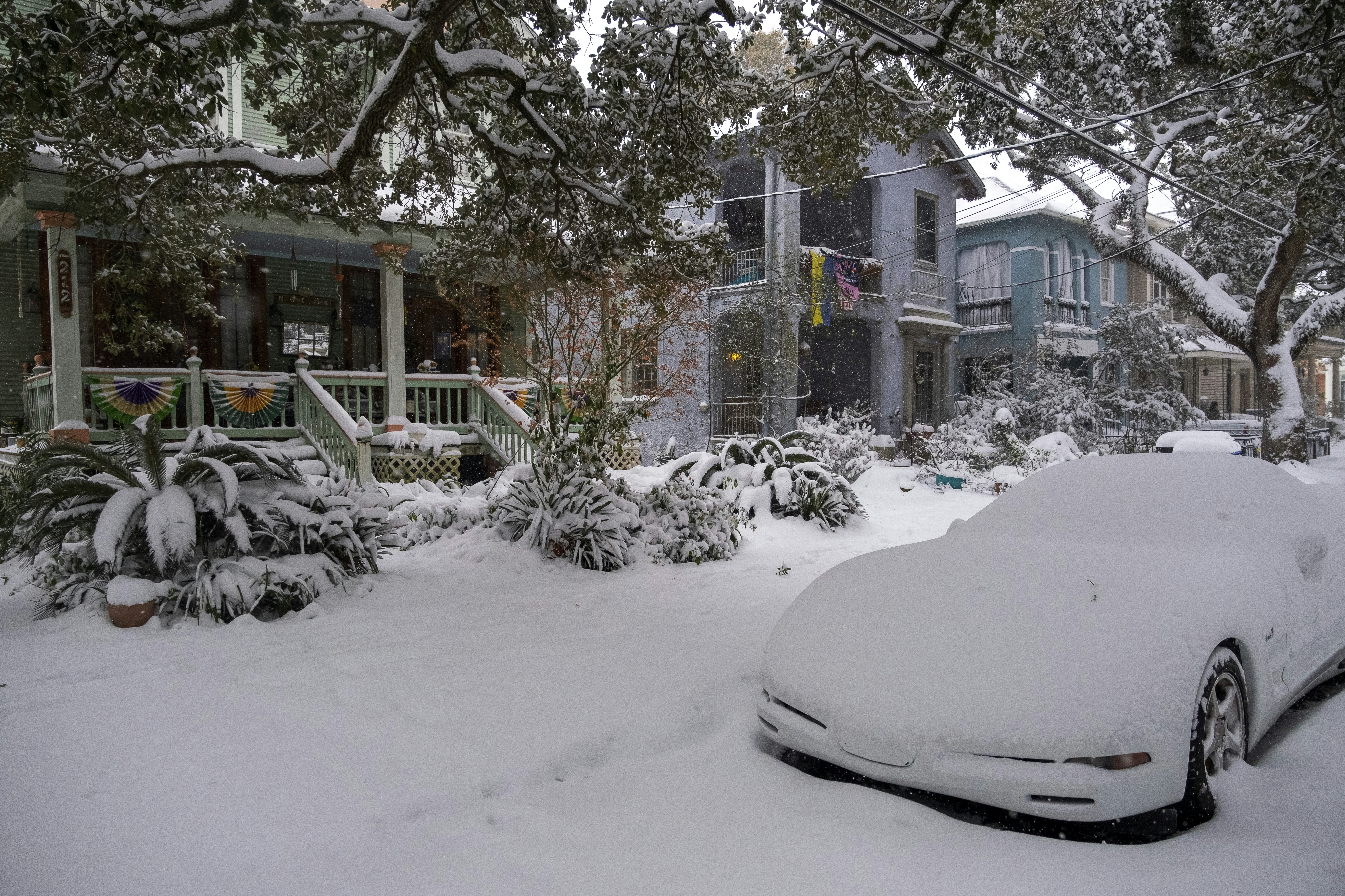 A car covered in snow parked in front of a house