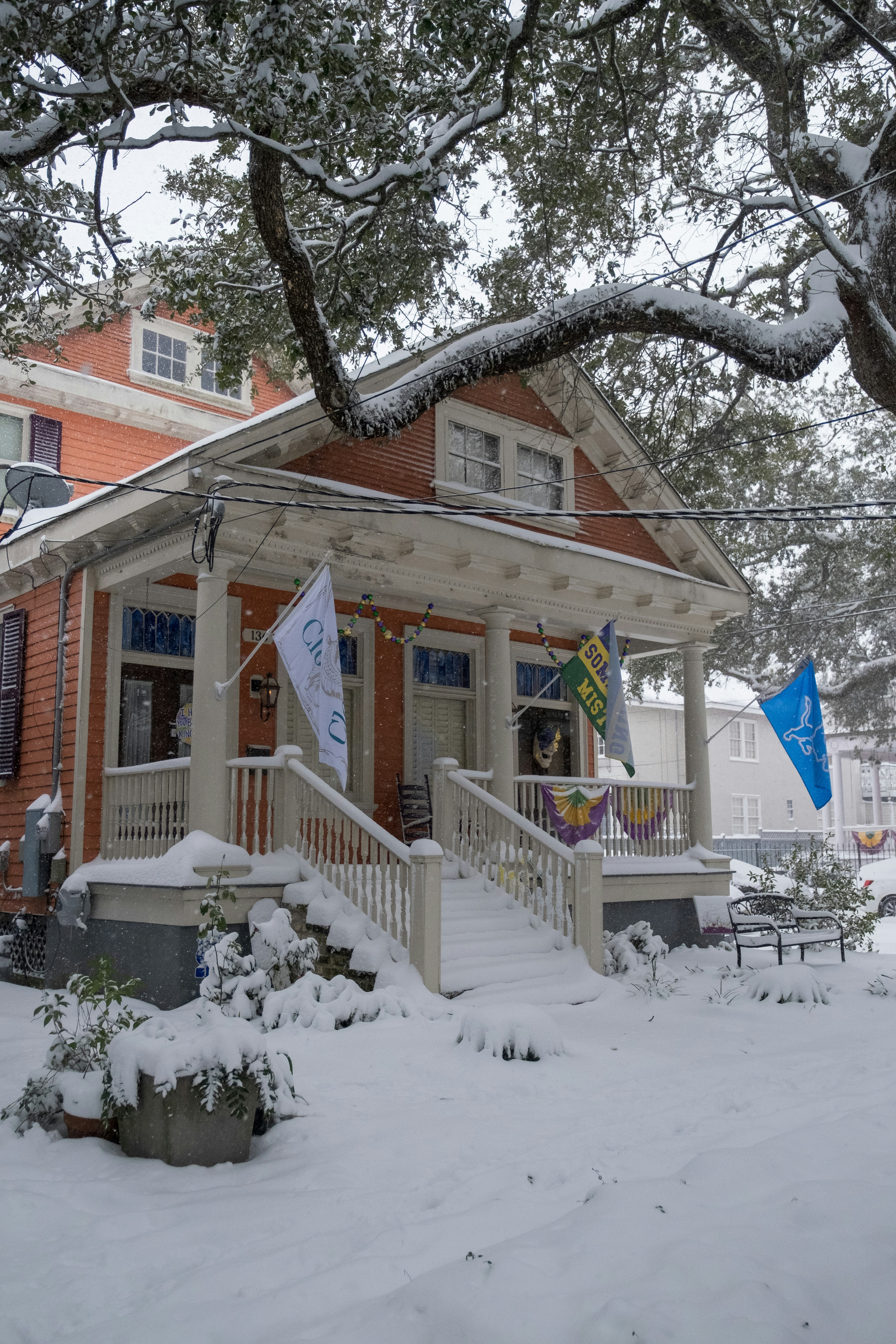 A house covered in snow next to a tree