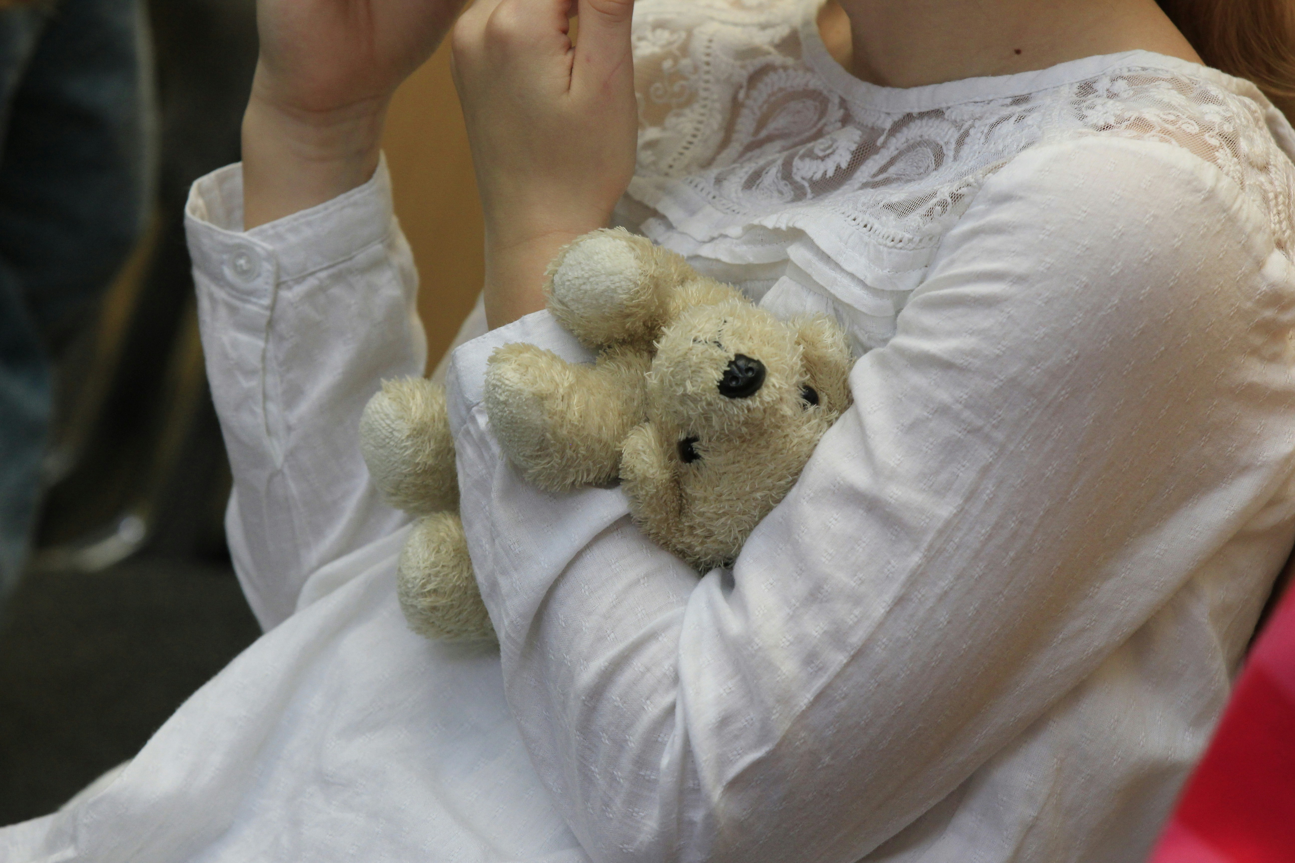 A woman in a white dress holding a teddy bear