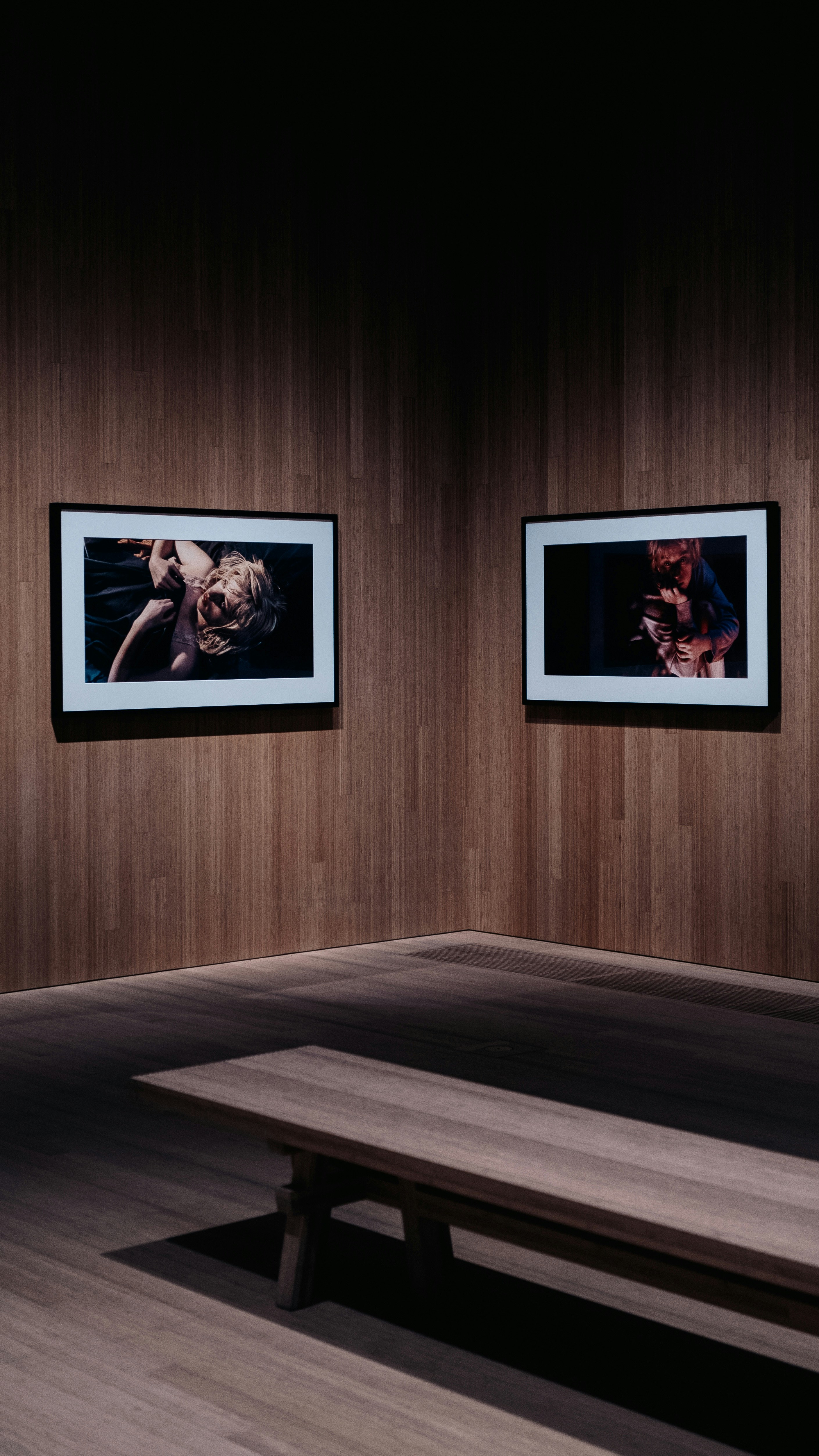 A wooden bench in a room with two pictures on the wall