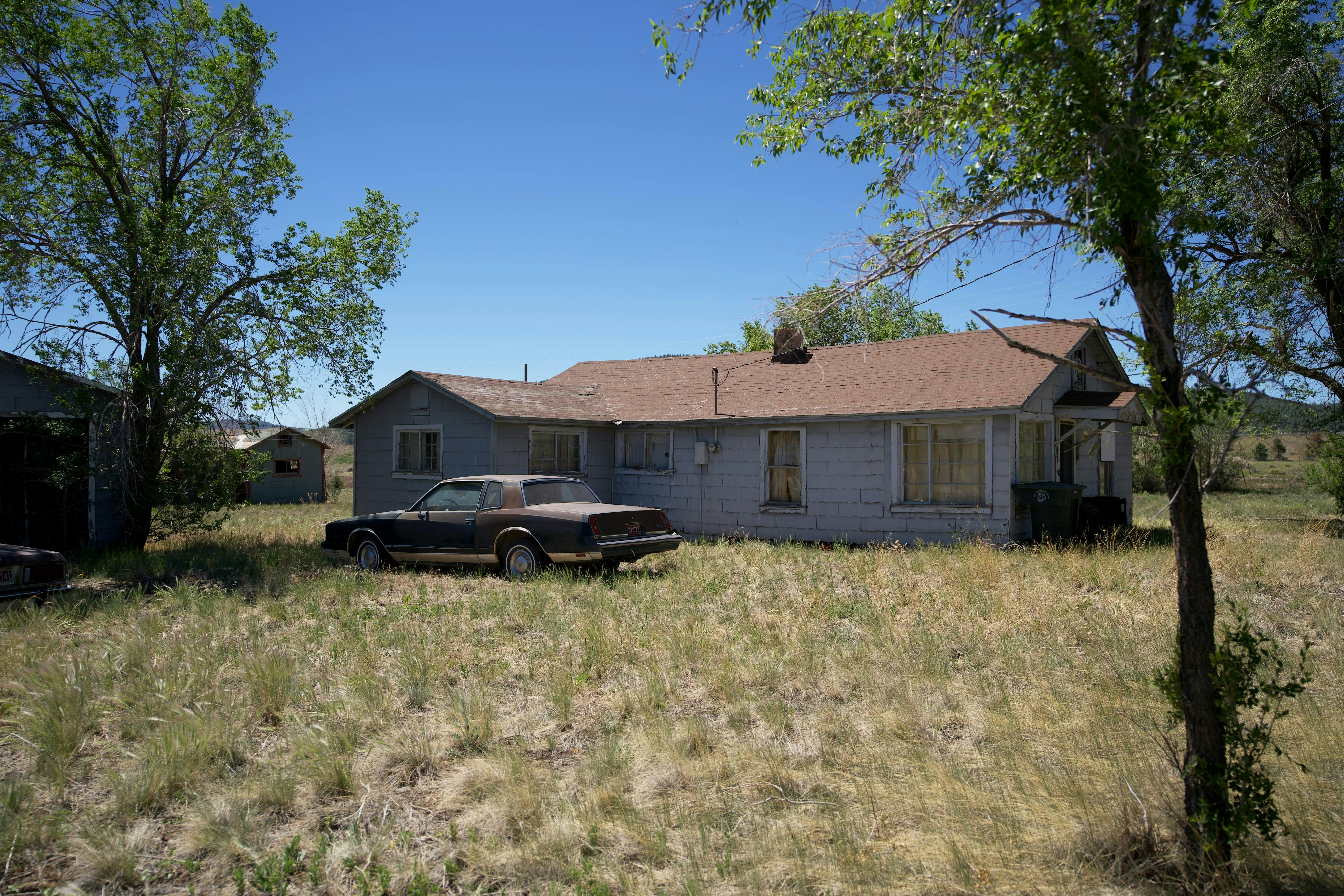 A car parked in front of a house in a field