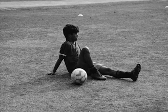 A young boy sitting on the ground with a soccer ball