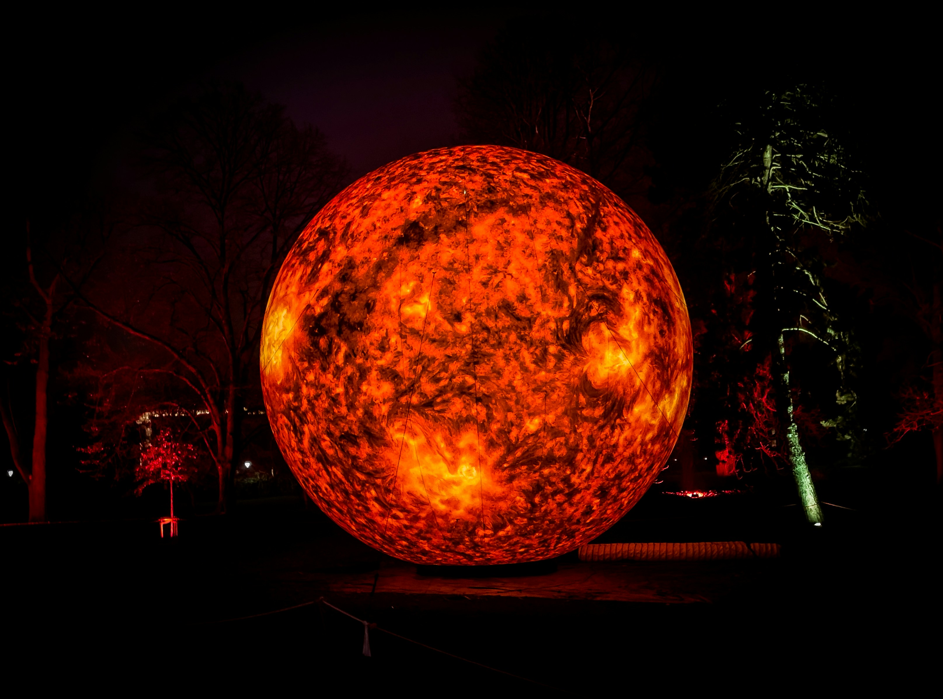 A large orange ball sitting in the middle of a park