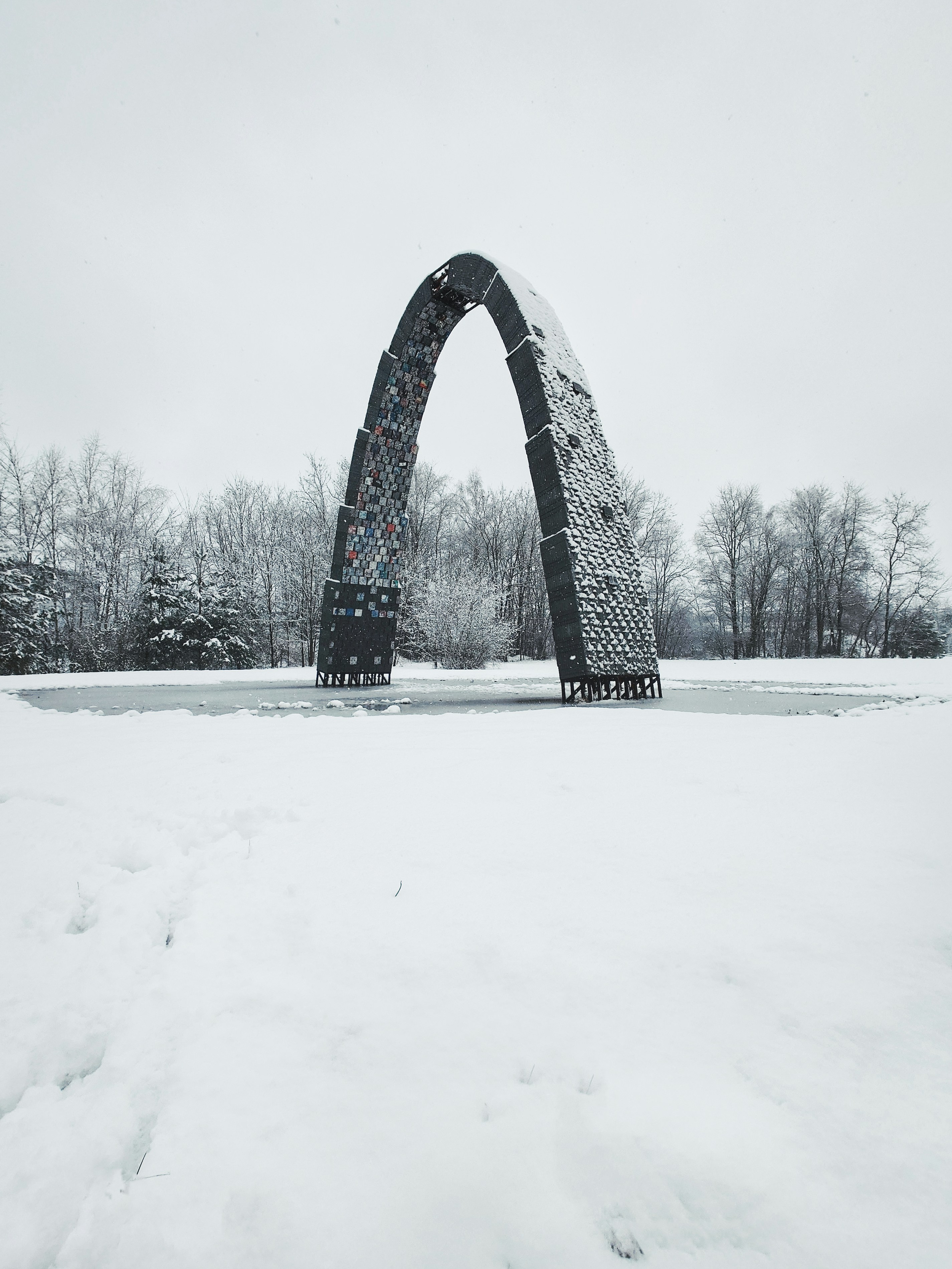 A large arch in the middle of a snowy field
