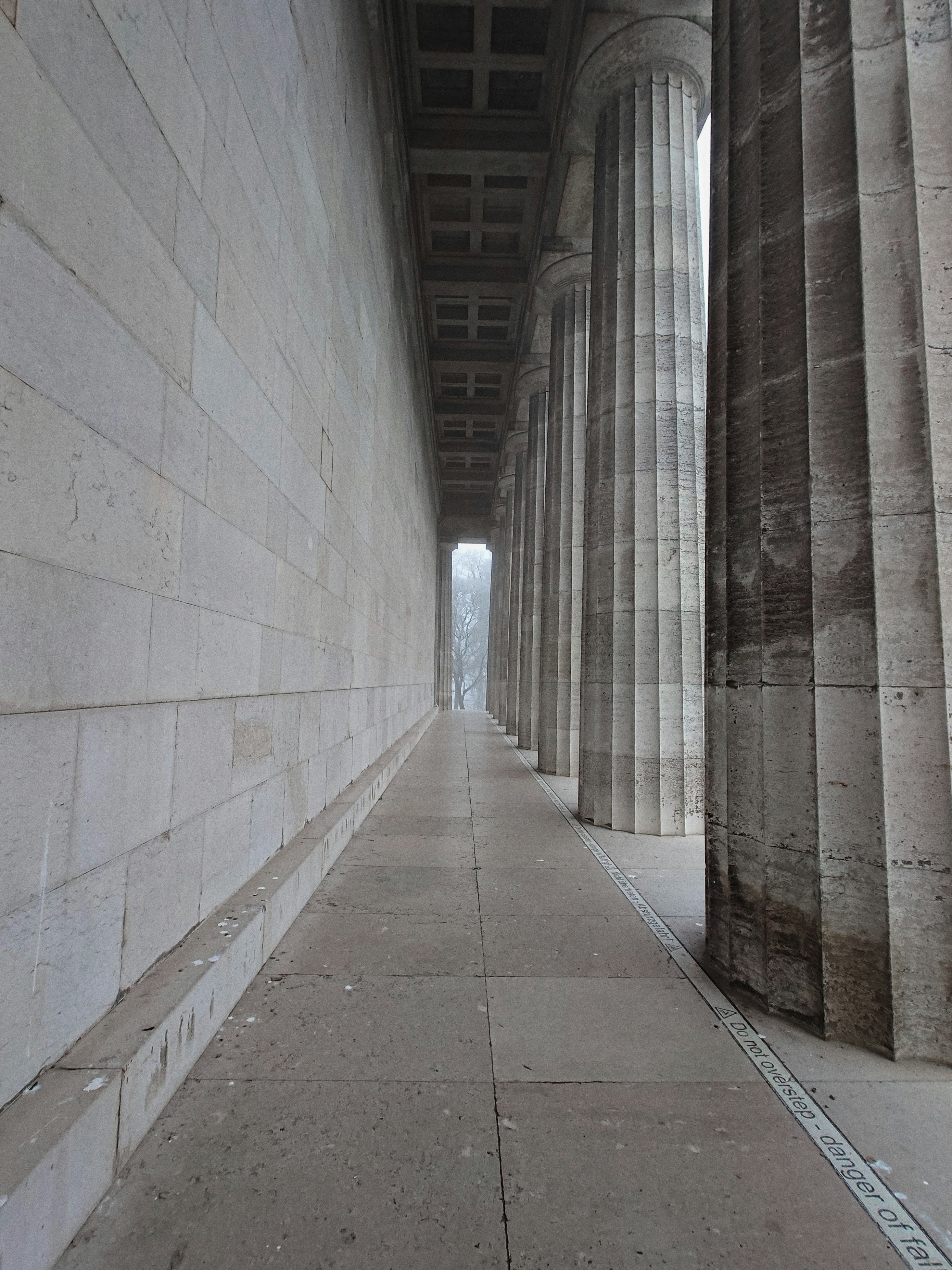A long hallway with columns and a clock on the wall