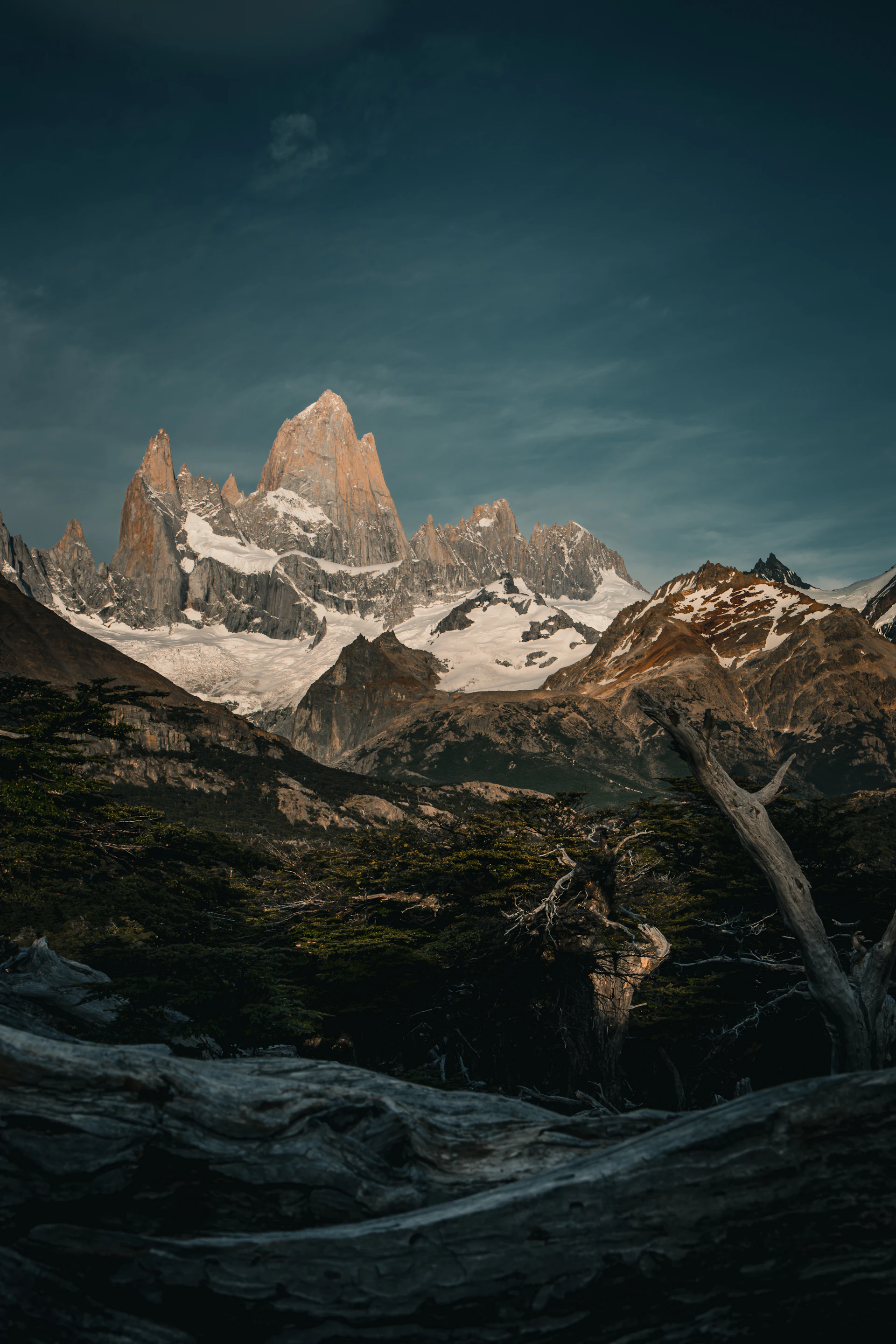 A mountain range covered in snow under a cloudy sky