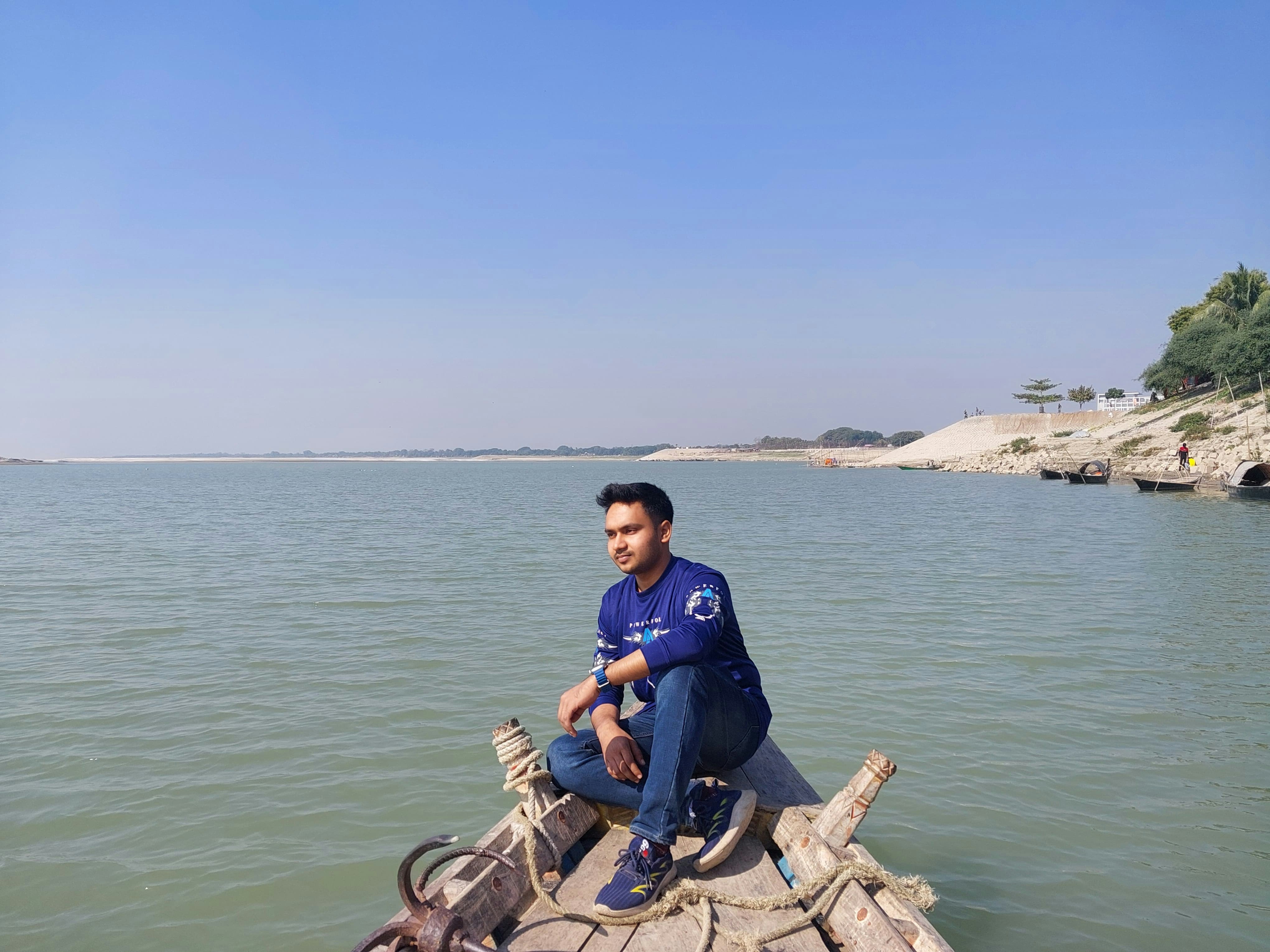 A man sitting on a rock in the middle of a body of water