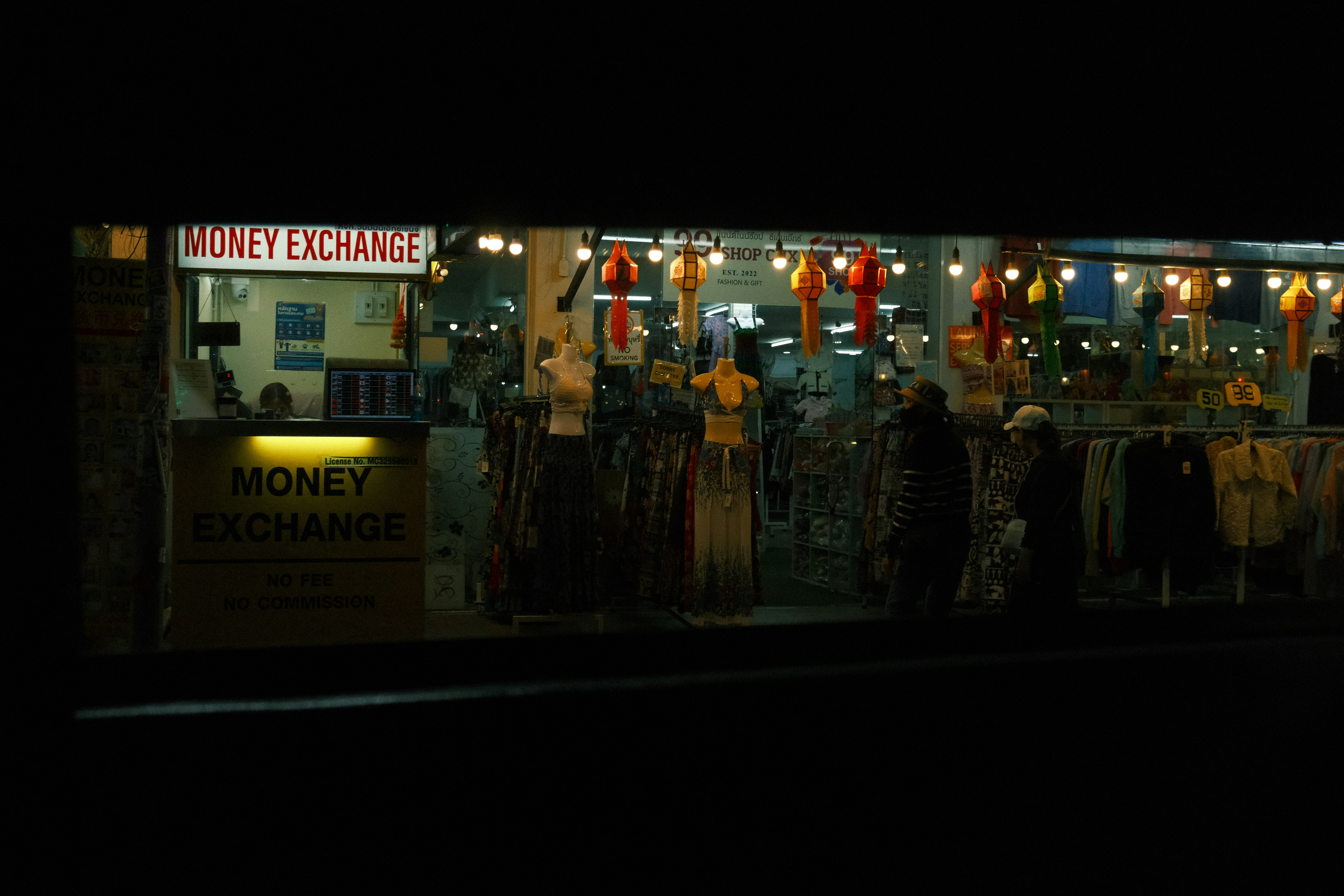 A group of people standing outside of a store at night