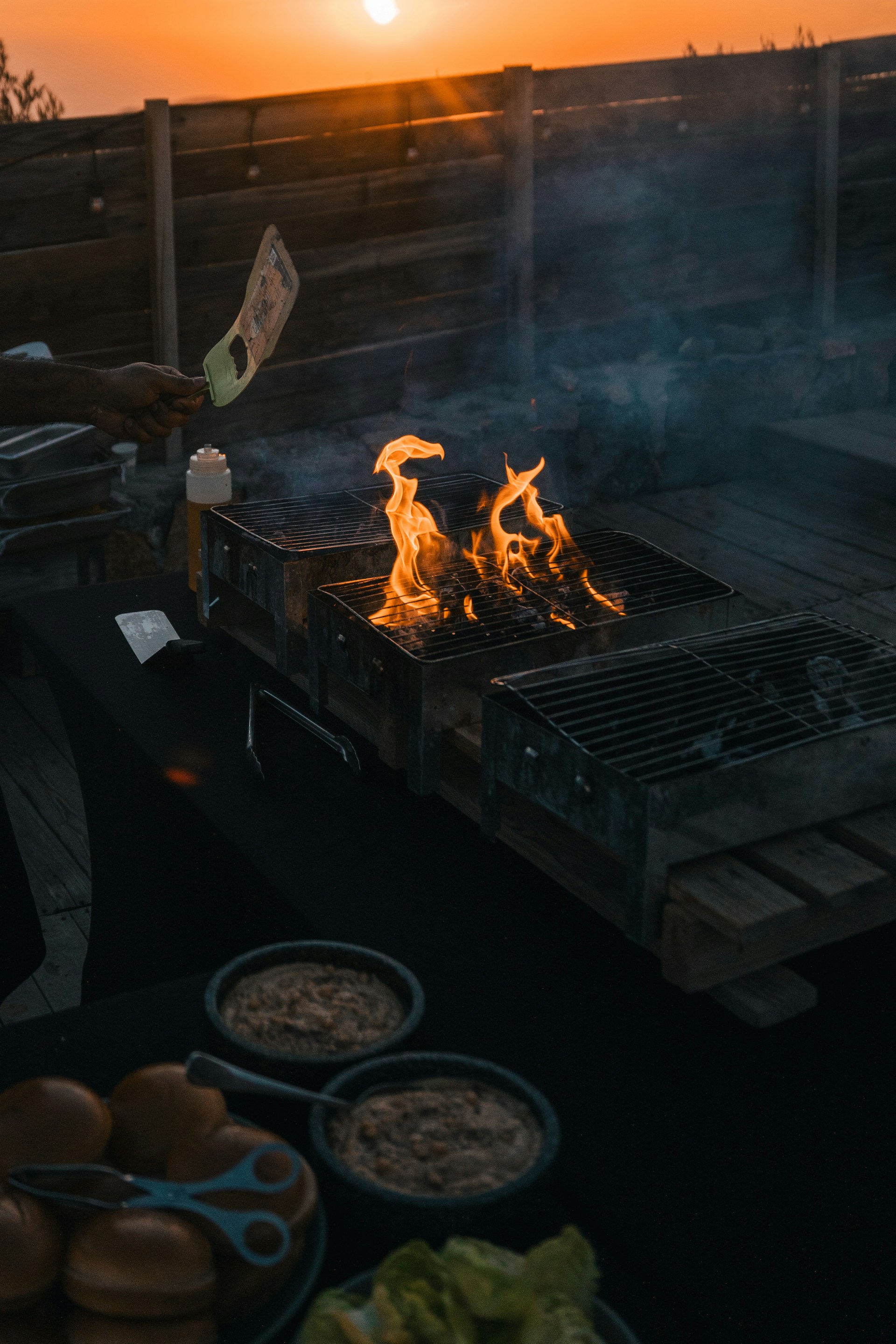 A person cooking food on a grill with a sunset in the background