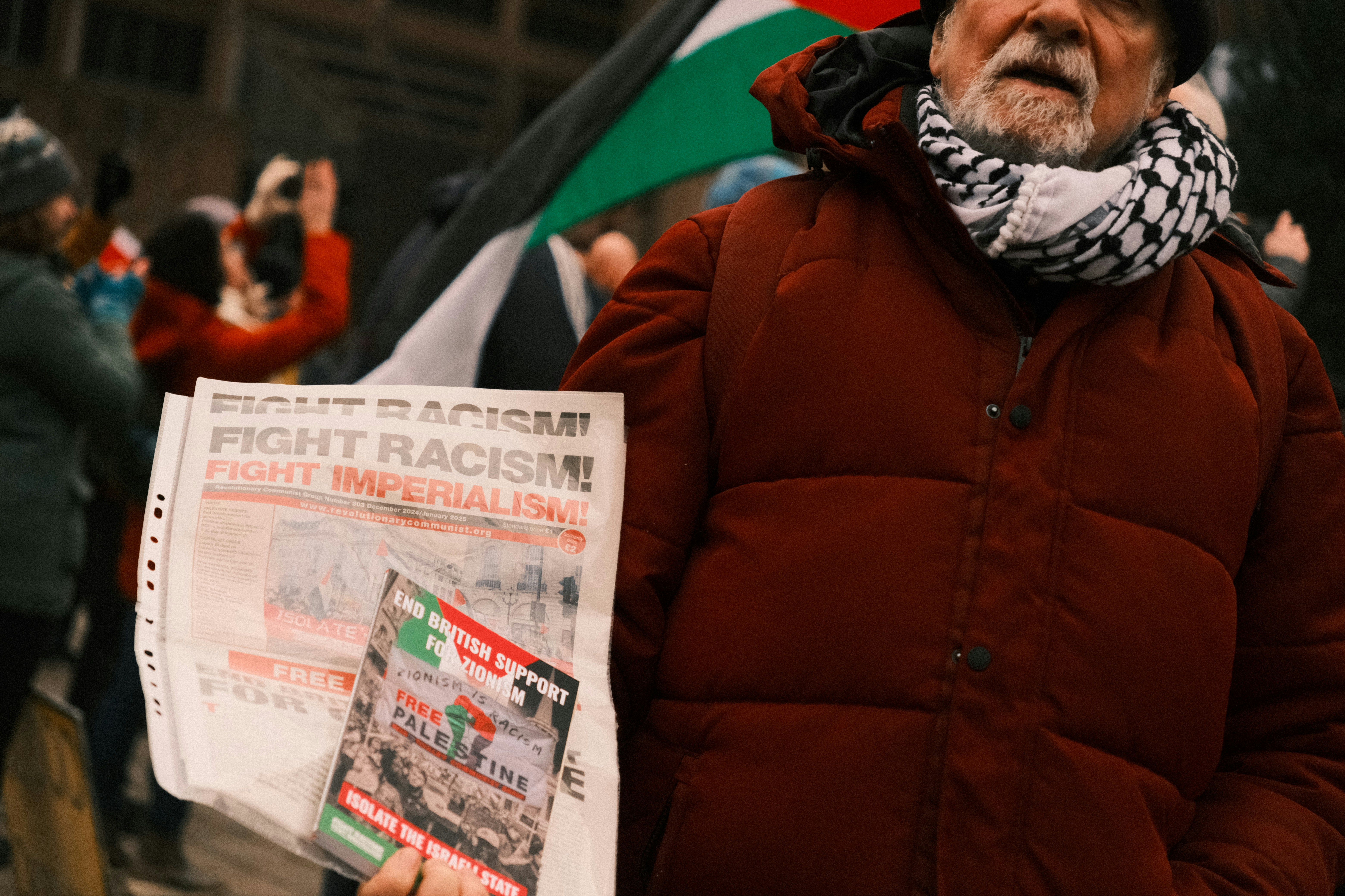 A man holding a newspaper and a scarf