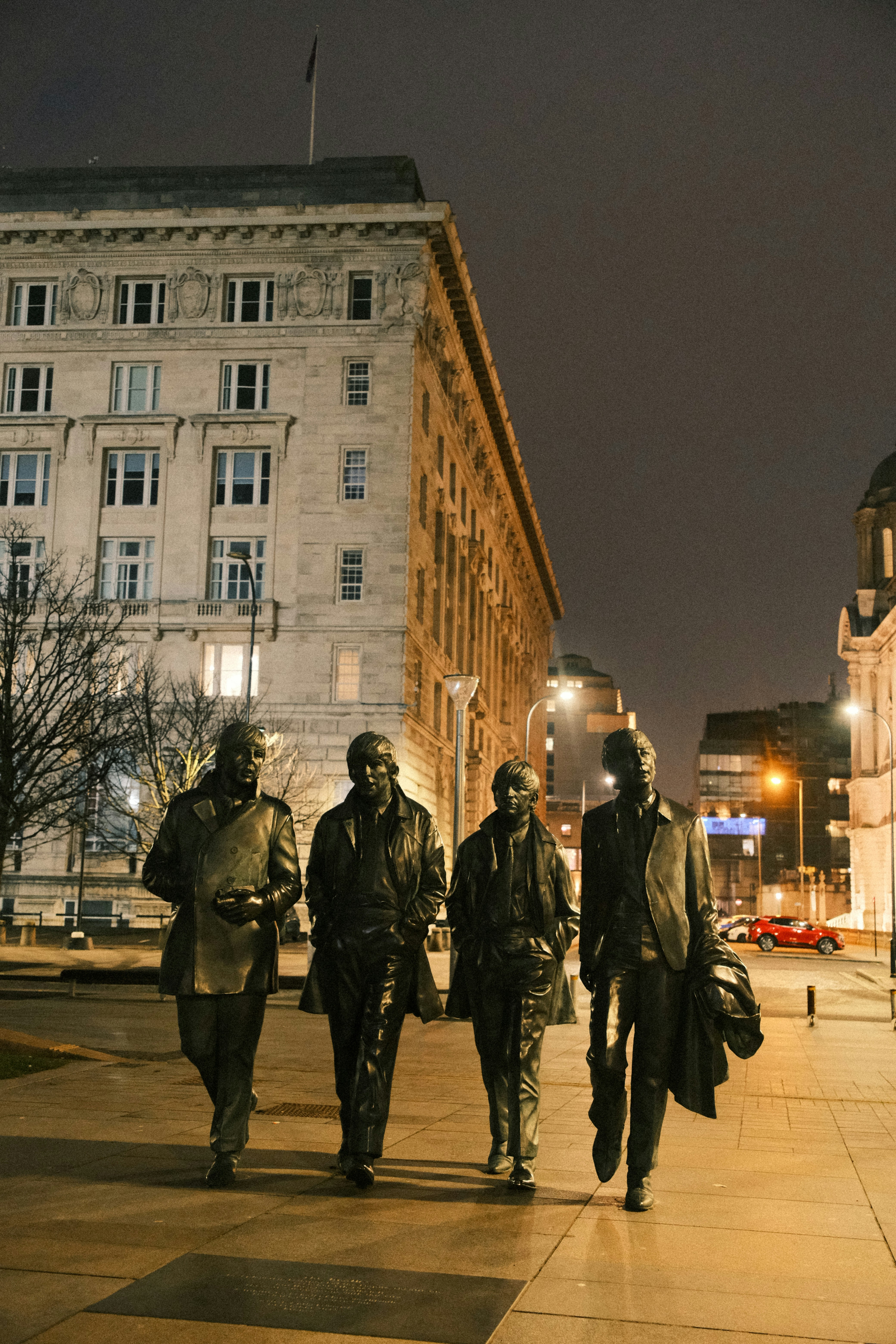 A group of men walking down a street next to tall buildings