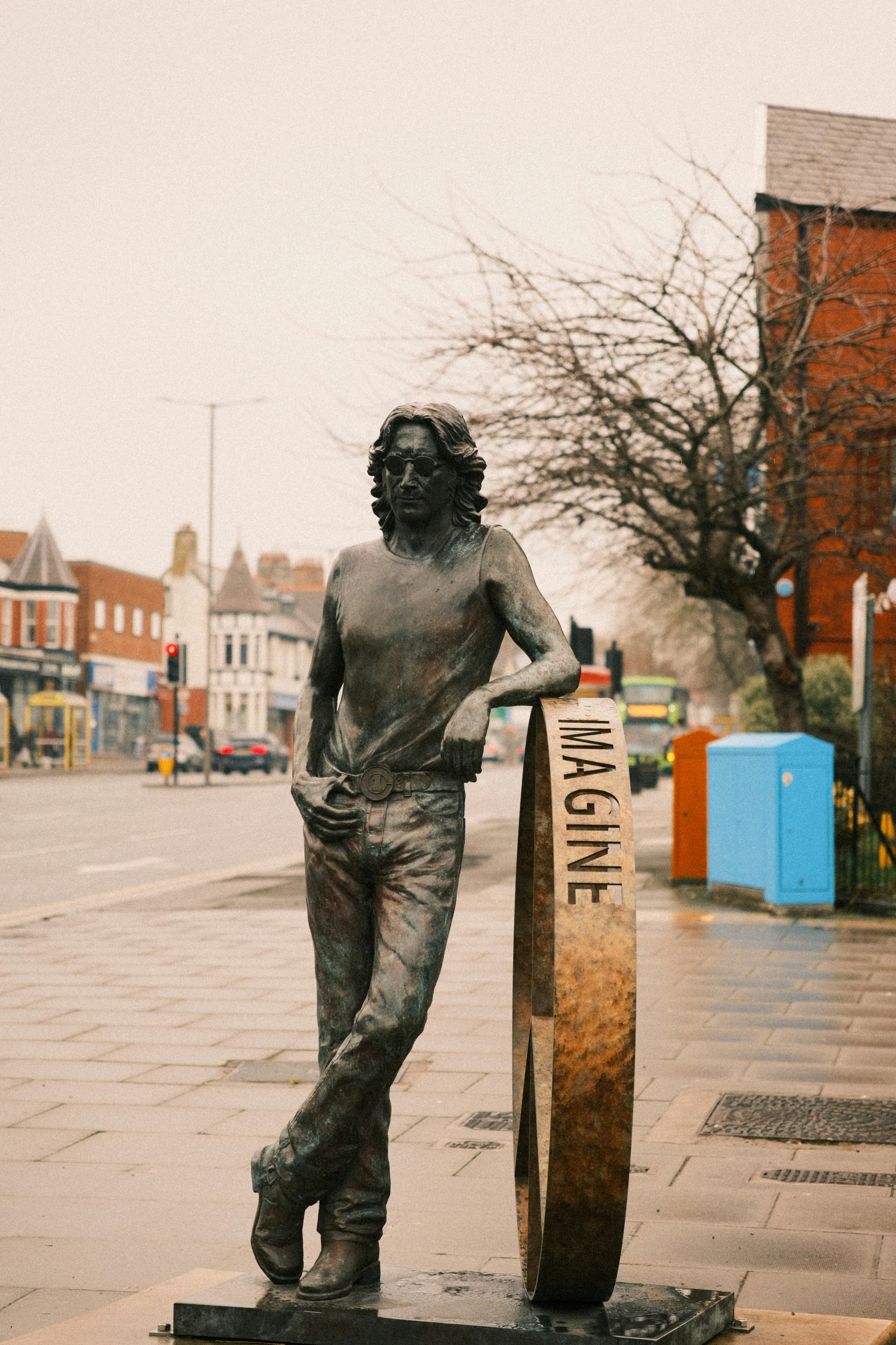 A statue of a man holding a surfboard on a sidewalk
