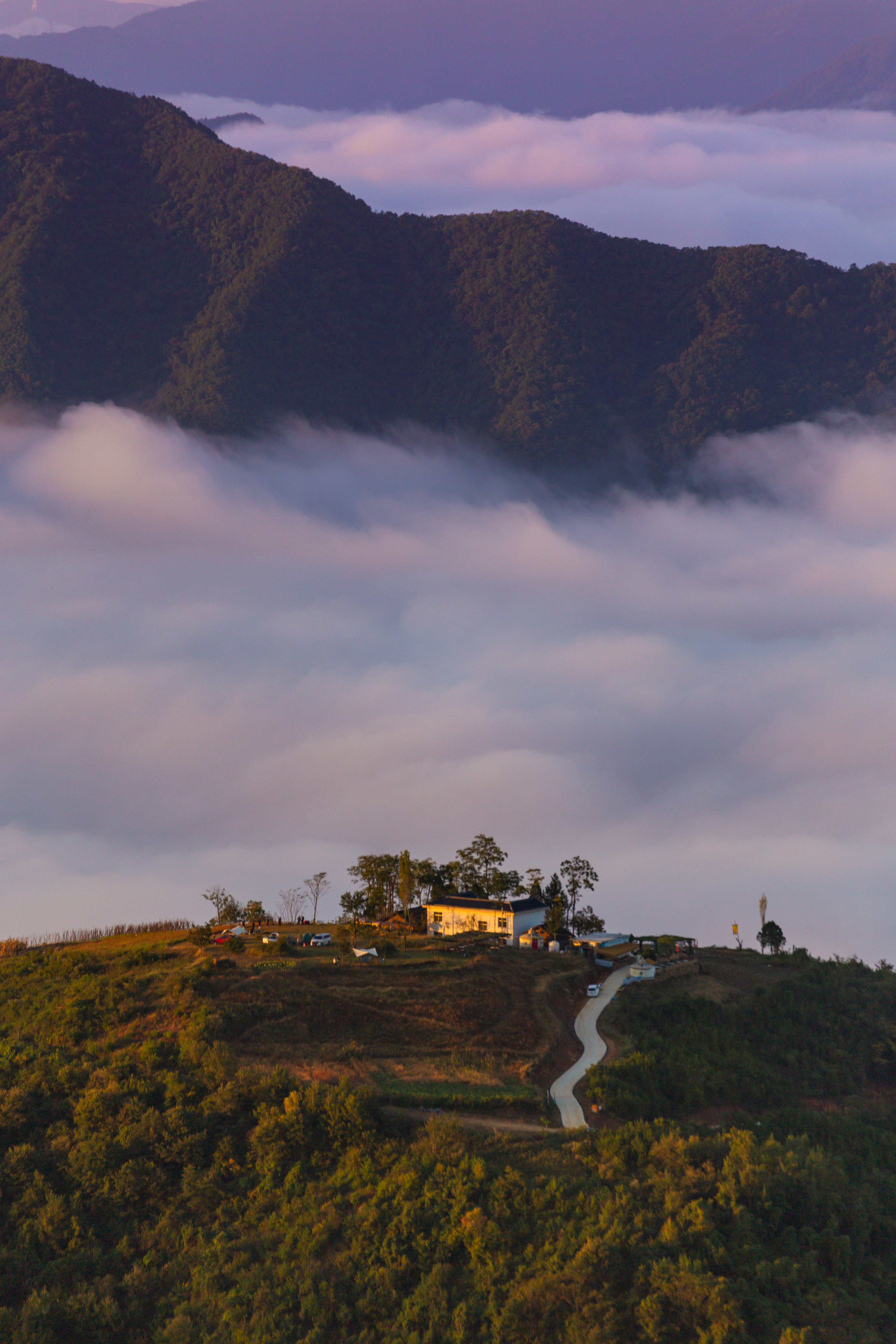 A hill with a house on top of it surrounded by clouds