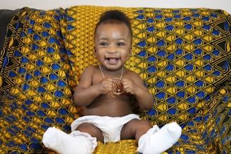 A baby sitting on a couch with a smile on his face