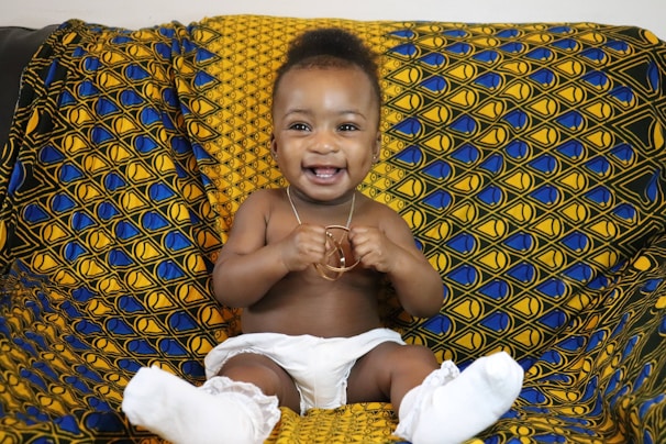 A baby sitting on a couch with a smile on his face