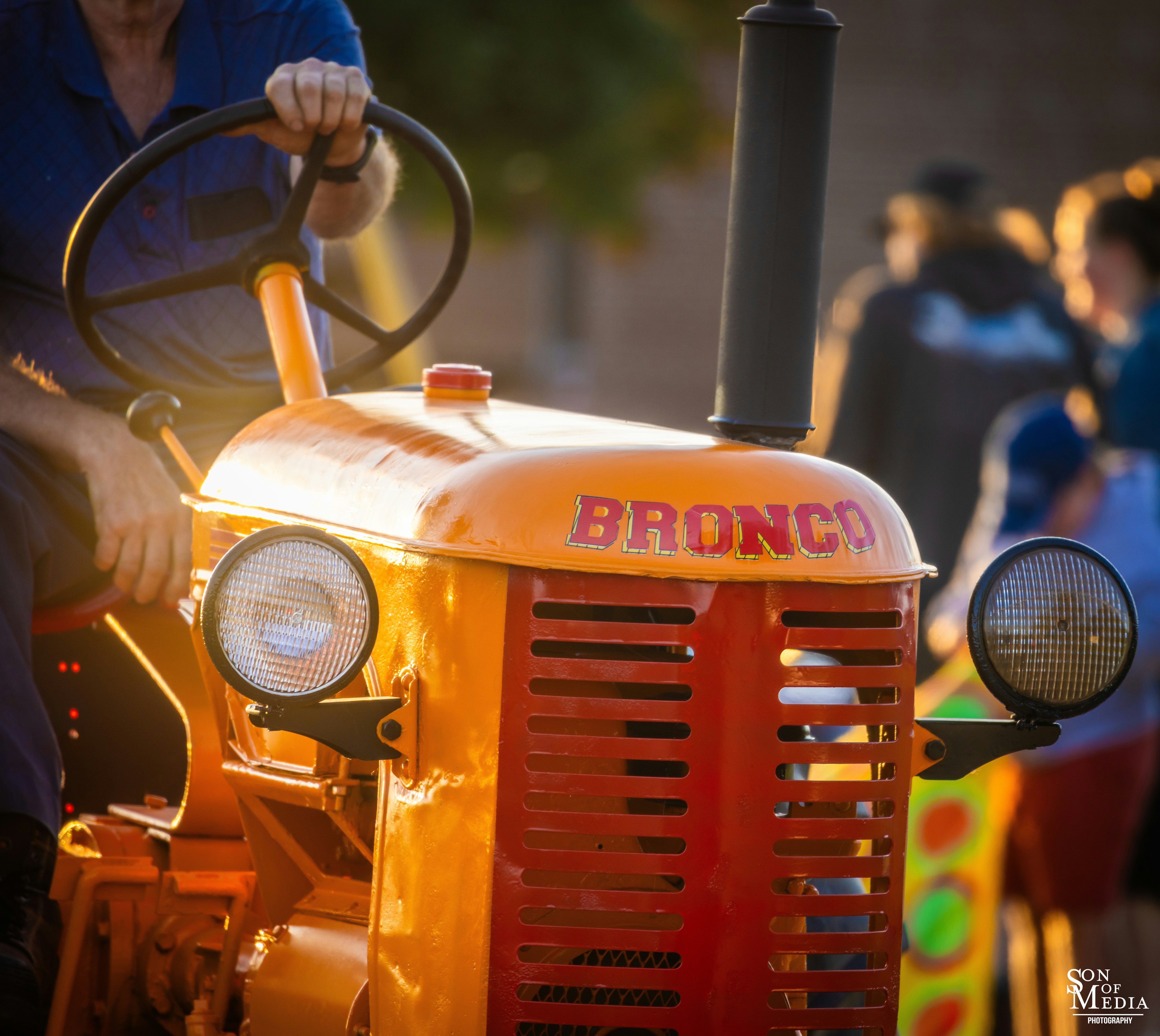 A man riding on the back of an orange tractor