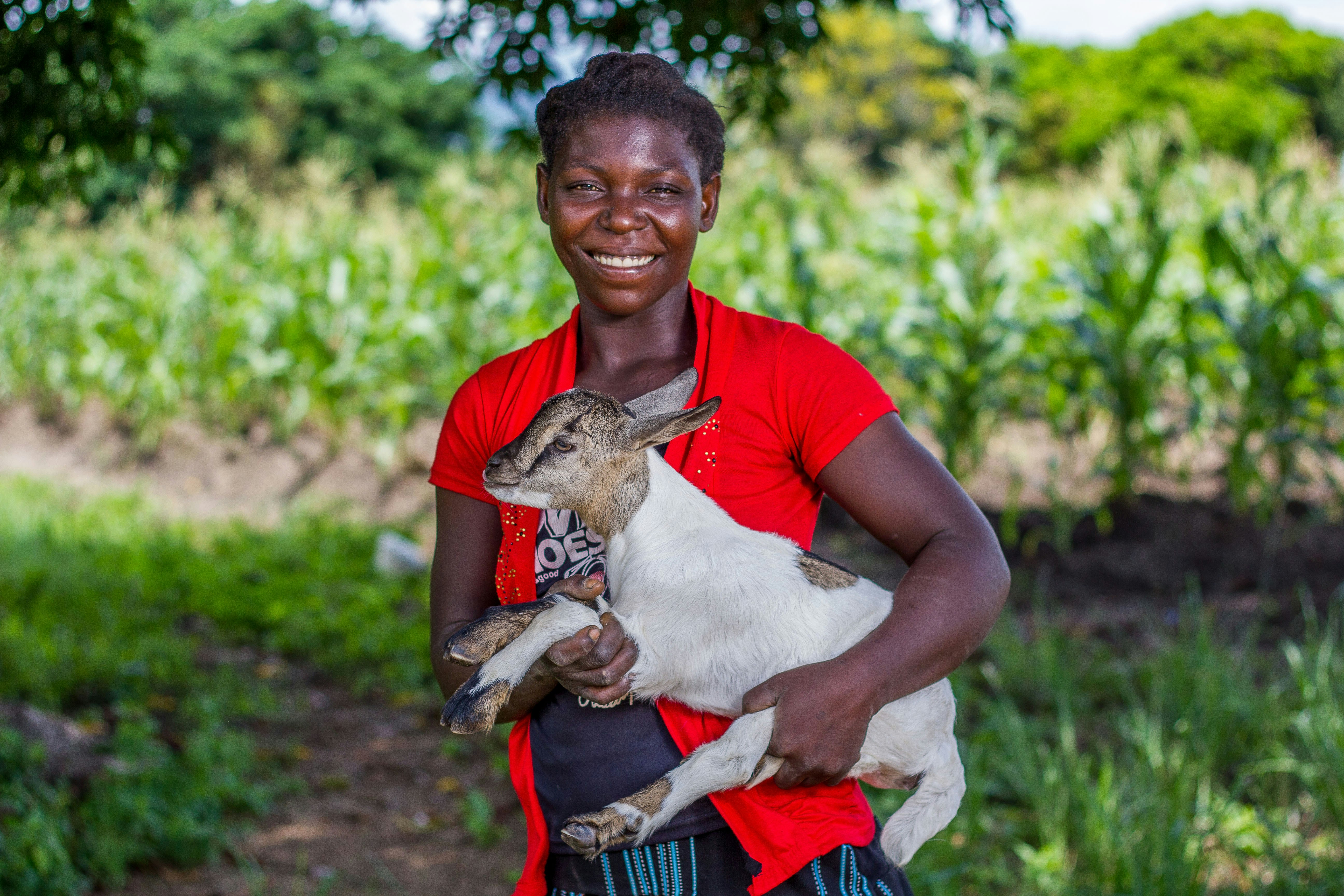 Una mujer sosteniendo un cabrito en sus brazos