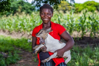 A woman holding a baby goat in her arms