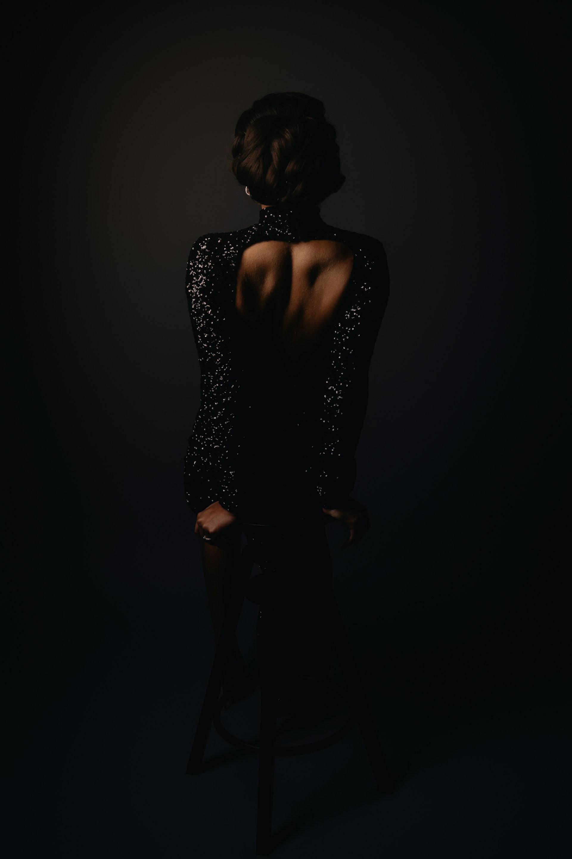 A woman standing in the dark with her back to the camera