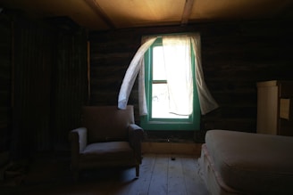 A bedroom with a chair and a window