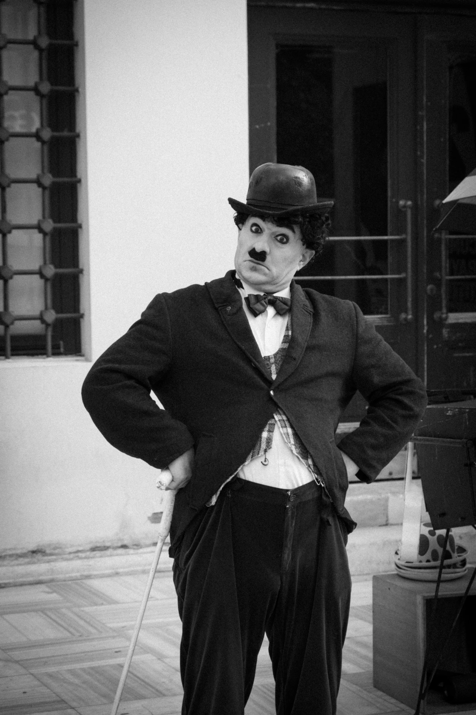 Homme en costume sombre, chapeau et canne, silhouette à la Charlot