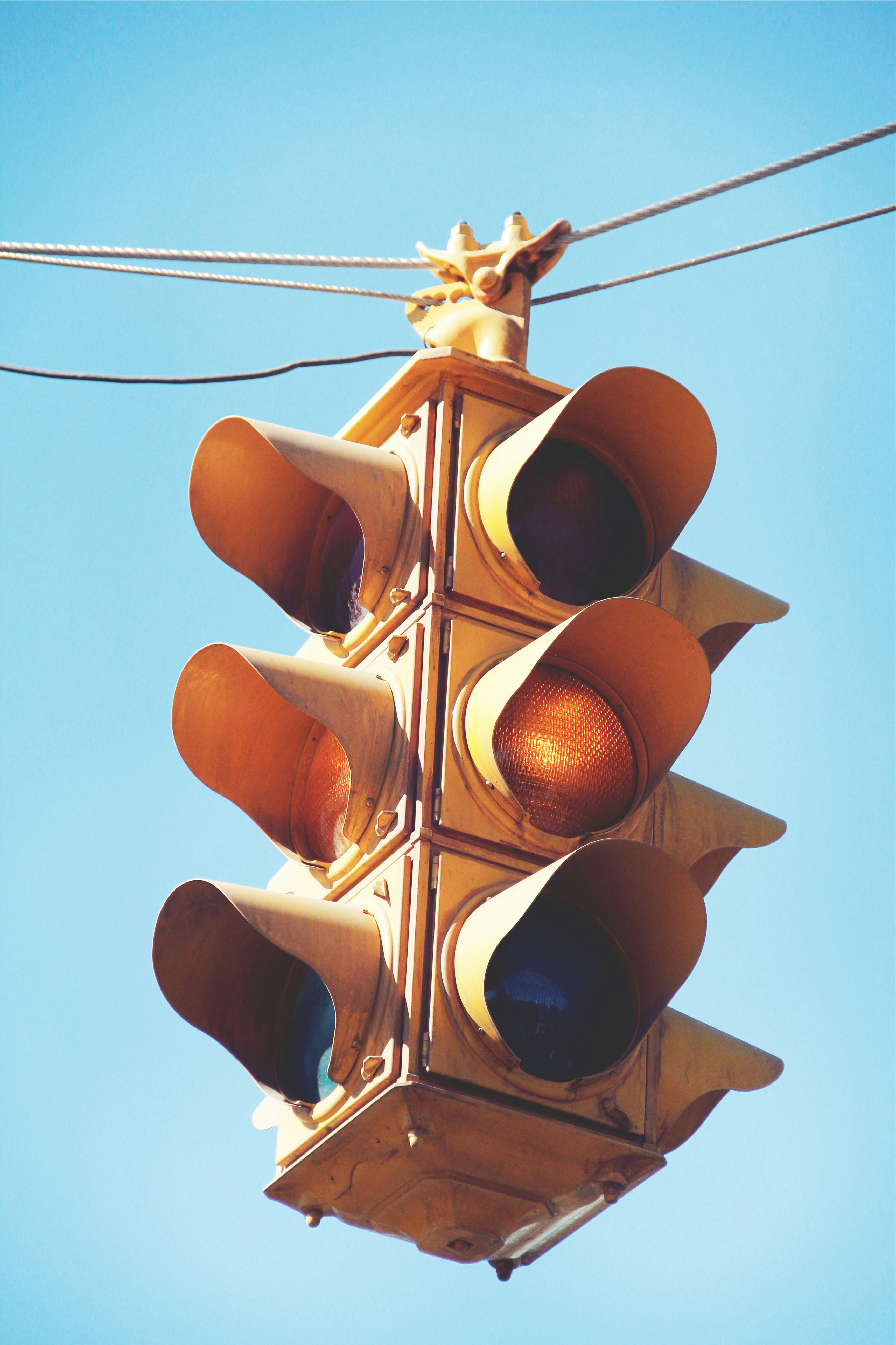 A traffic light hanging from a wire with a blue sky in the background