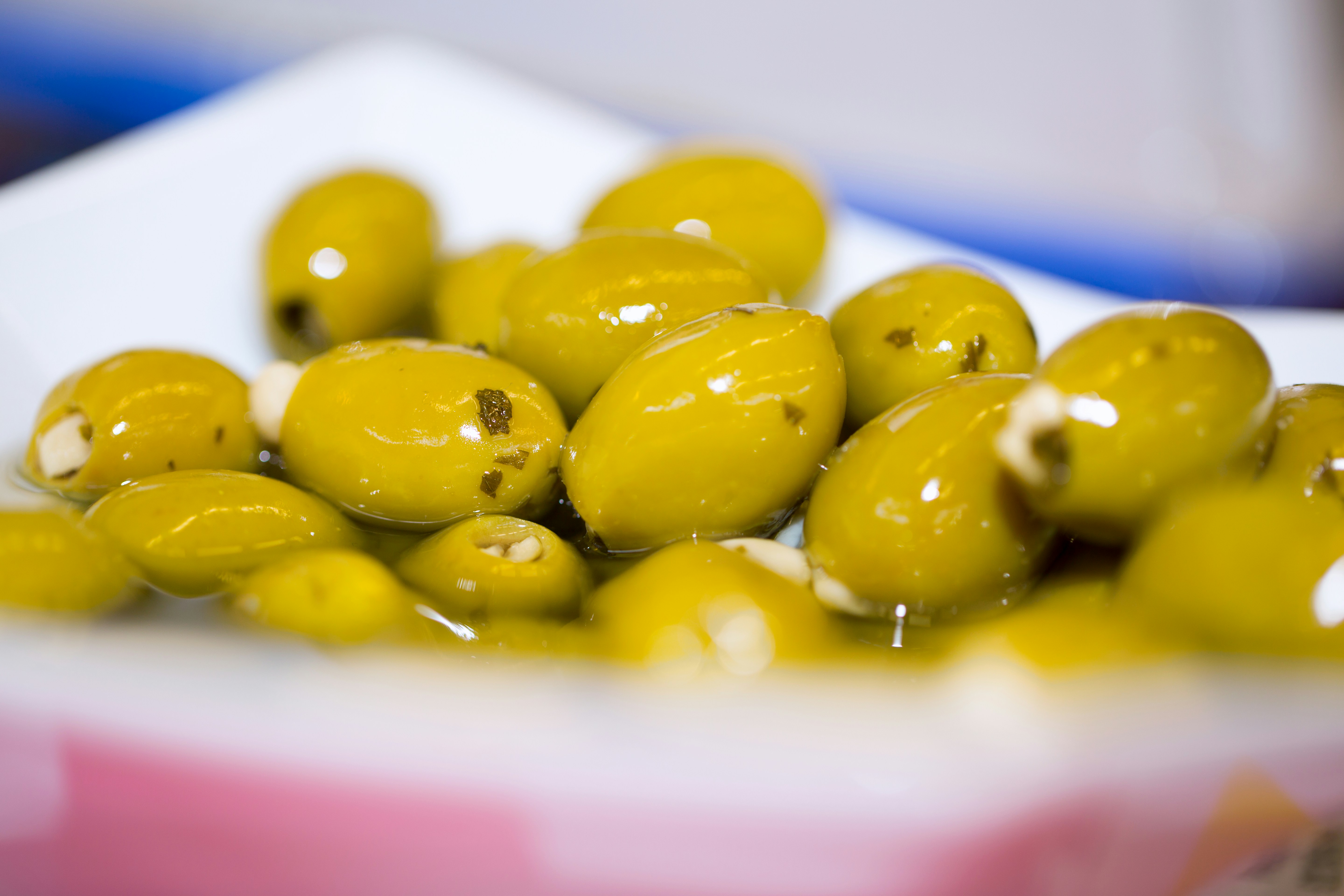 A white bowl filled with green olives sitting on top of a table