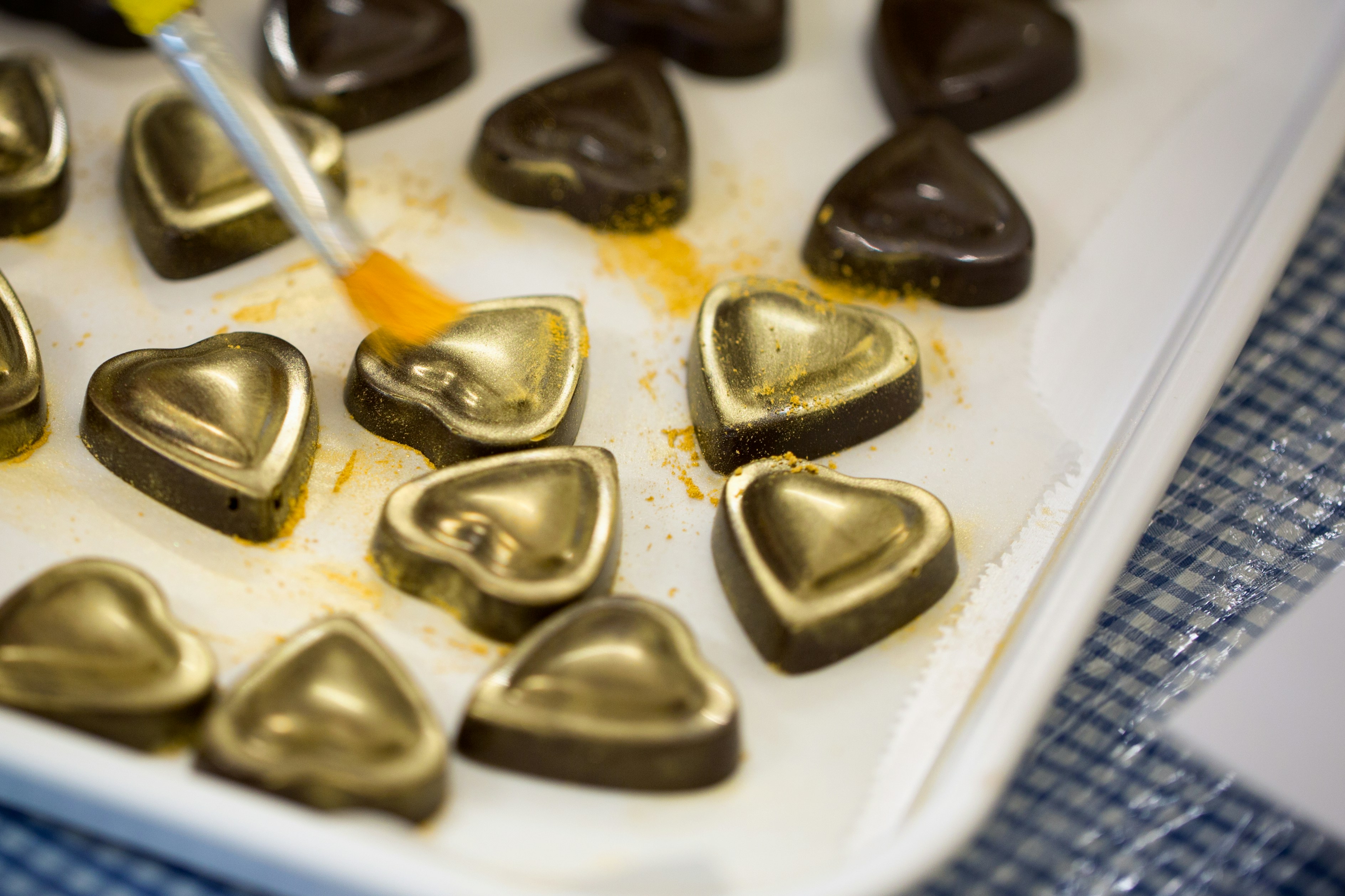 Un vassoio di cioccolatini a forma di cuore che viene immerso con un pennello