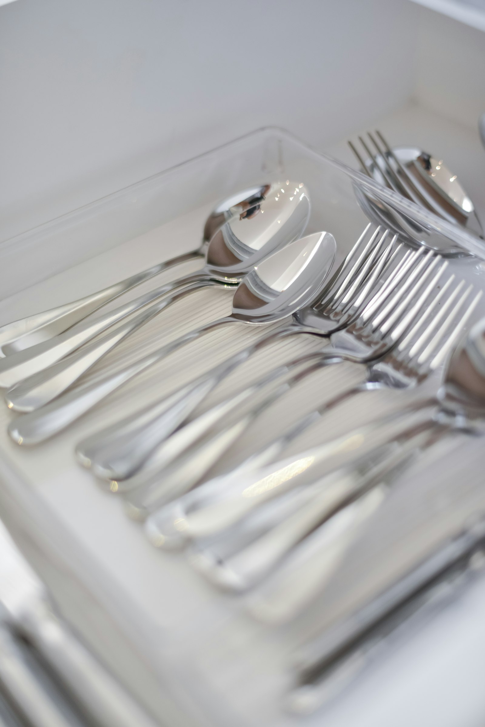 Silver cutlery sorted neatly in a white drawer tray