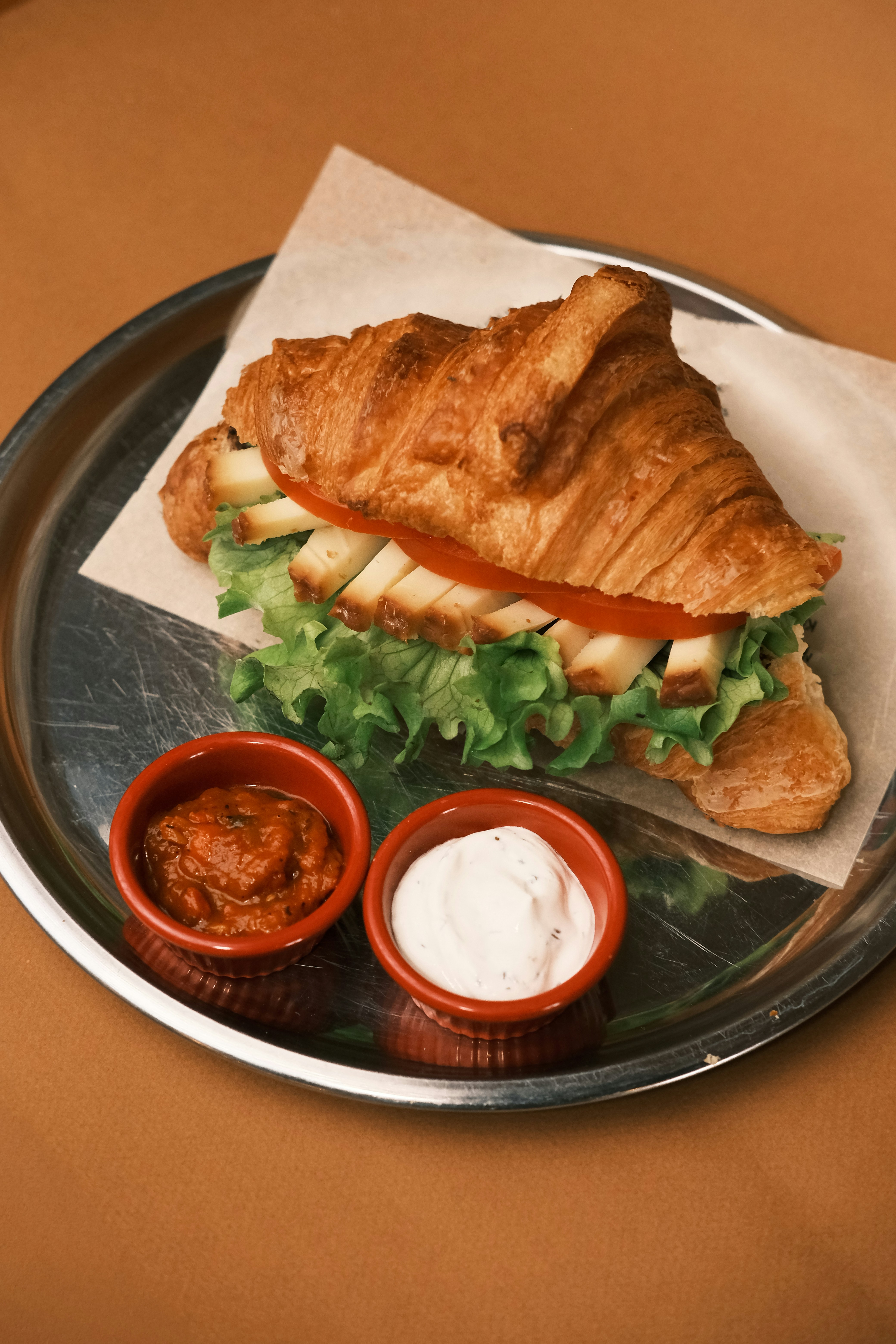 A croissant sandwich with lettuce and tomato on a plate