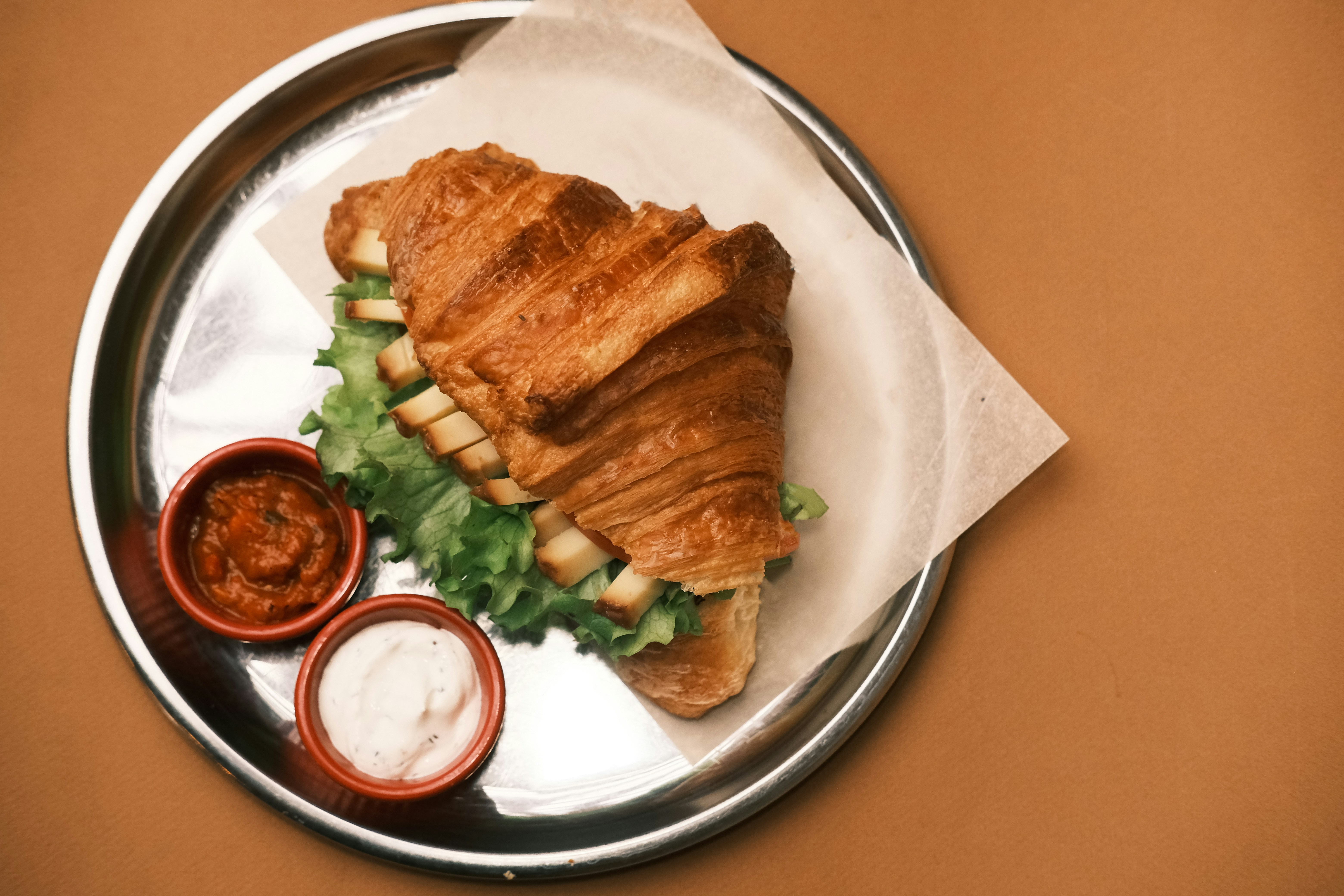 A croissant sandwich with lettuce and tomato sauce on a plate