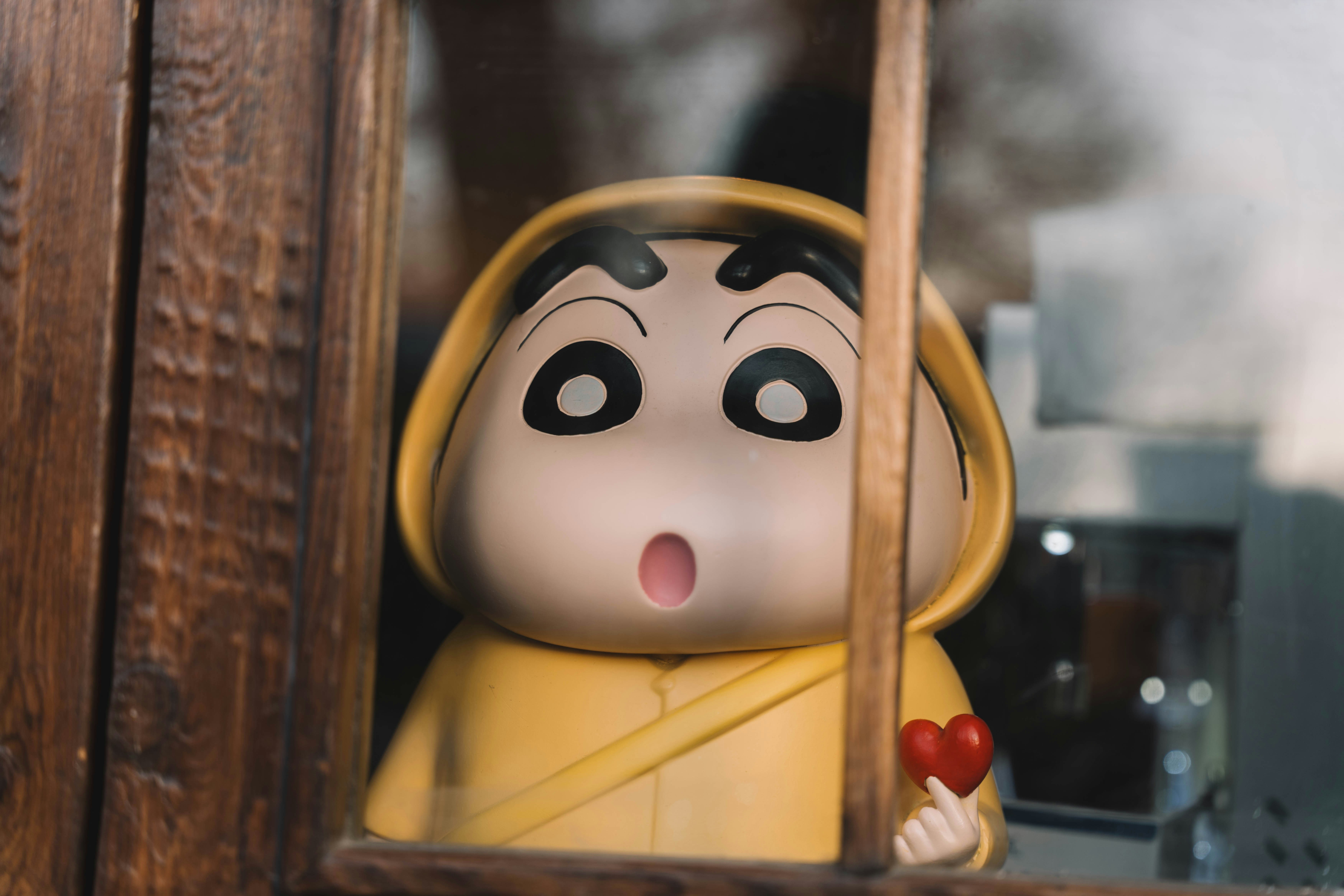 A small doll in a window with a surprised look on its face
