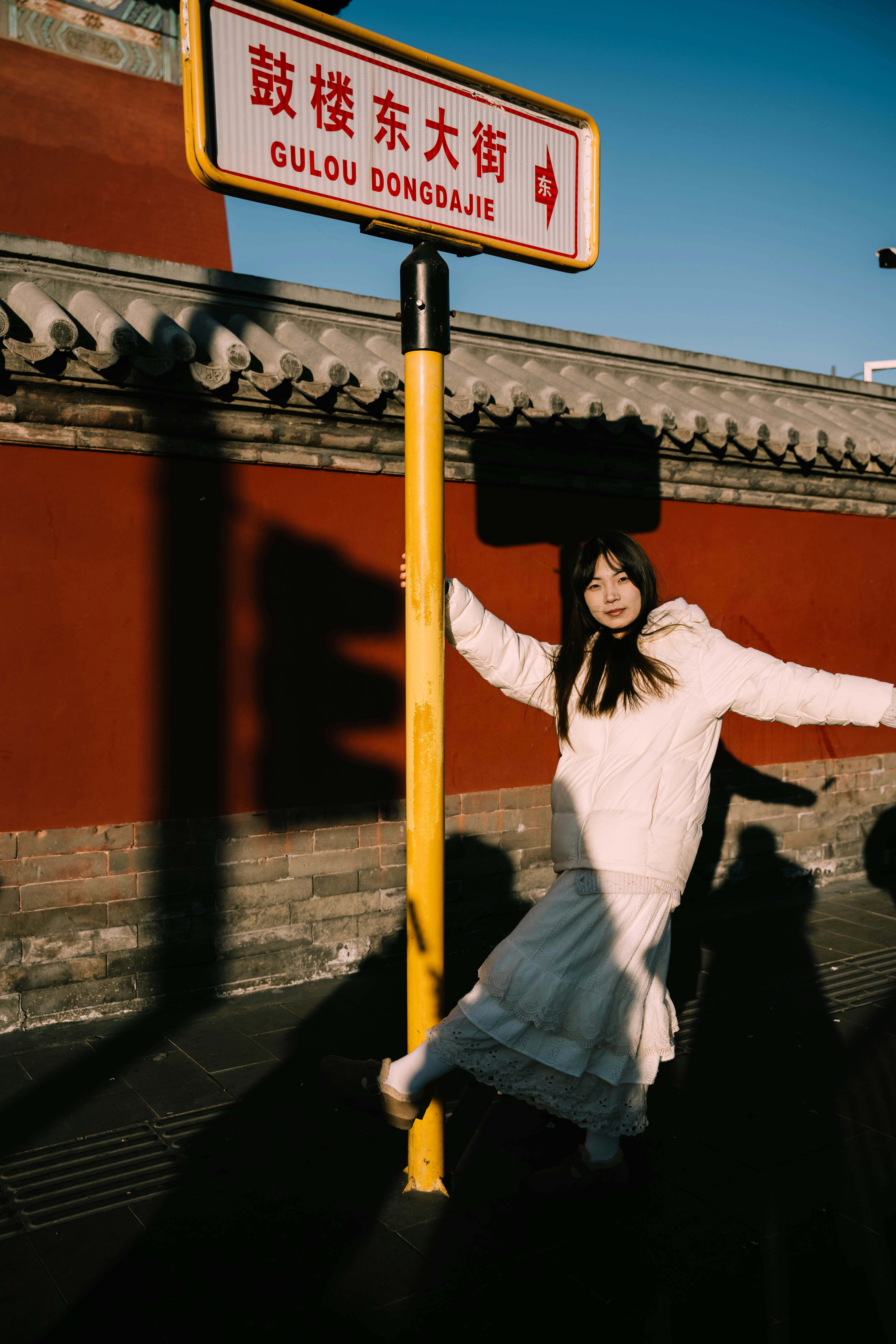 A woman in a white dress standing next to a street sign