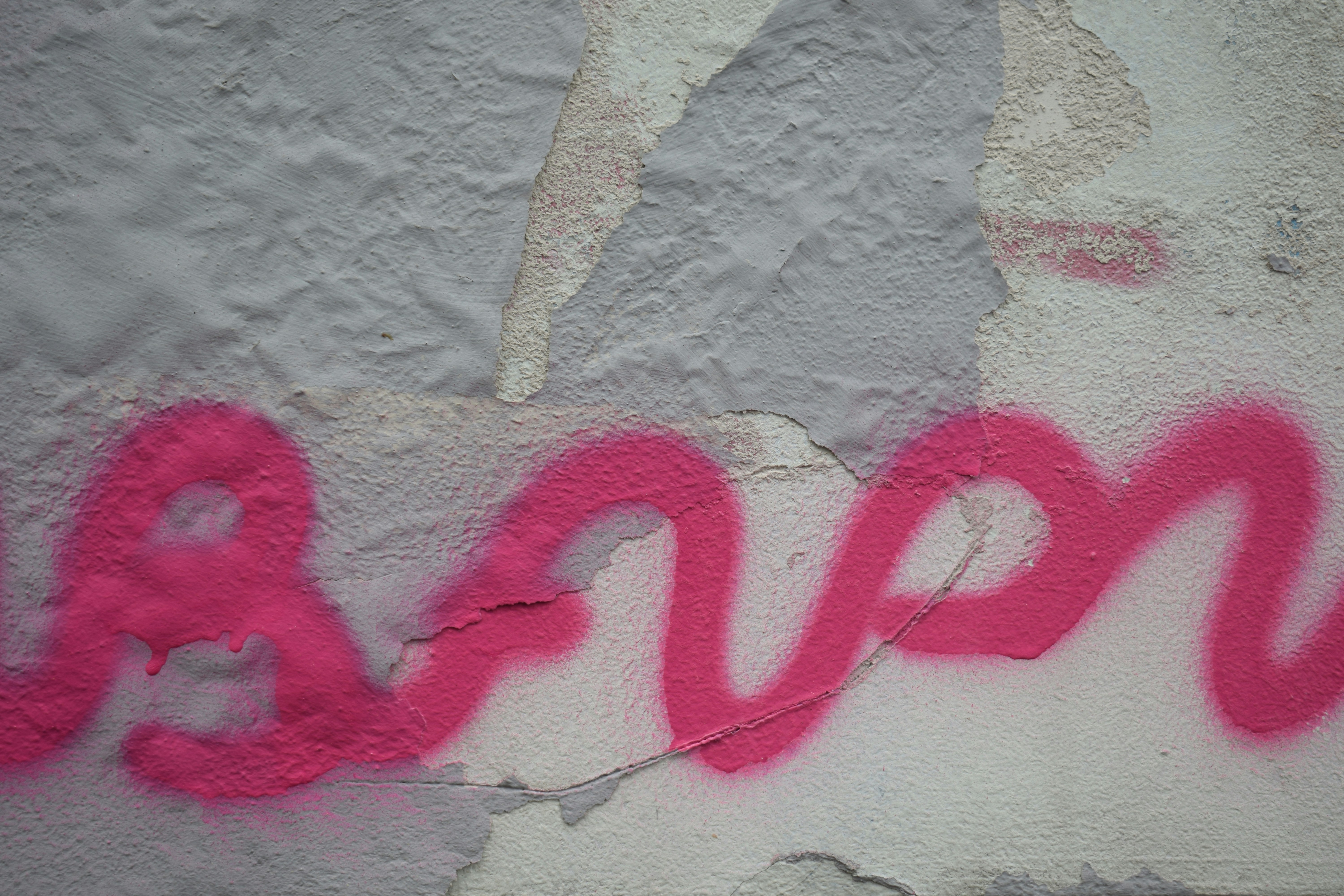 A wall that has some pink graffiti on it