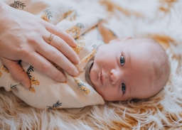 A woman holding a baby on top of a blanket