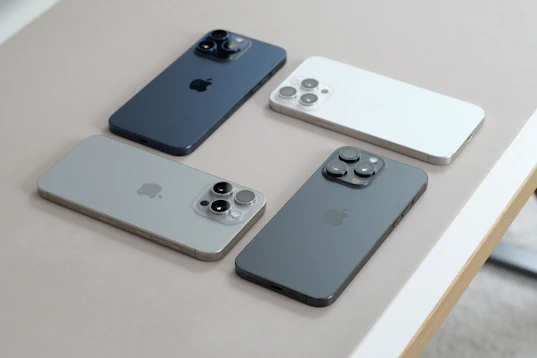A table topped with four different colored cell phones