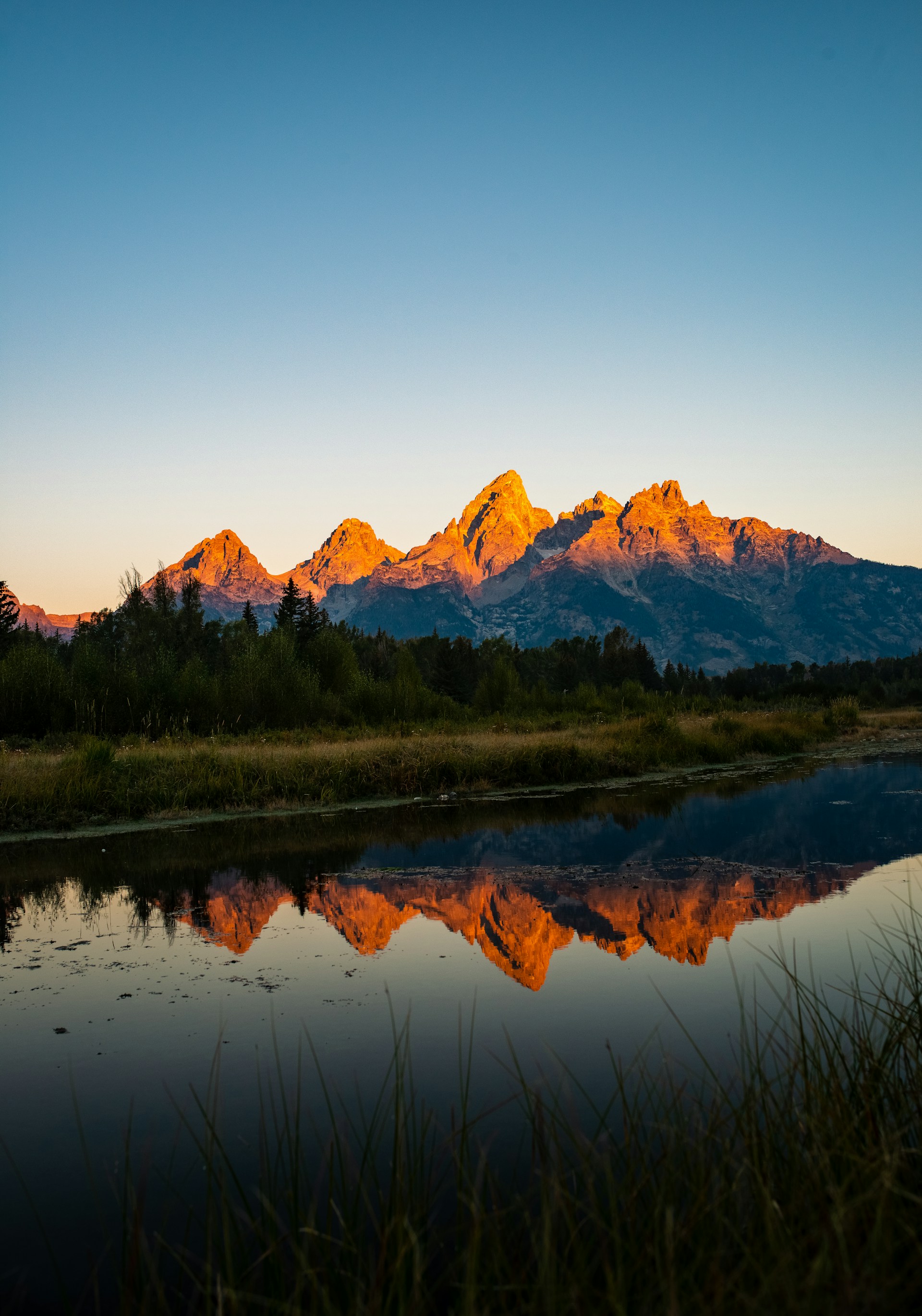 The mountains are reflected in the still water of the river