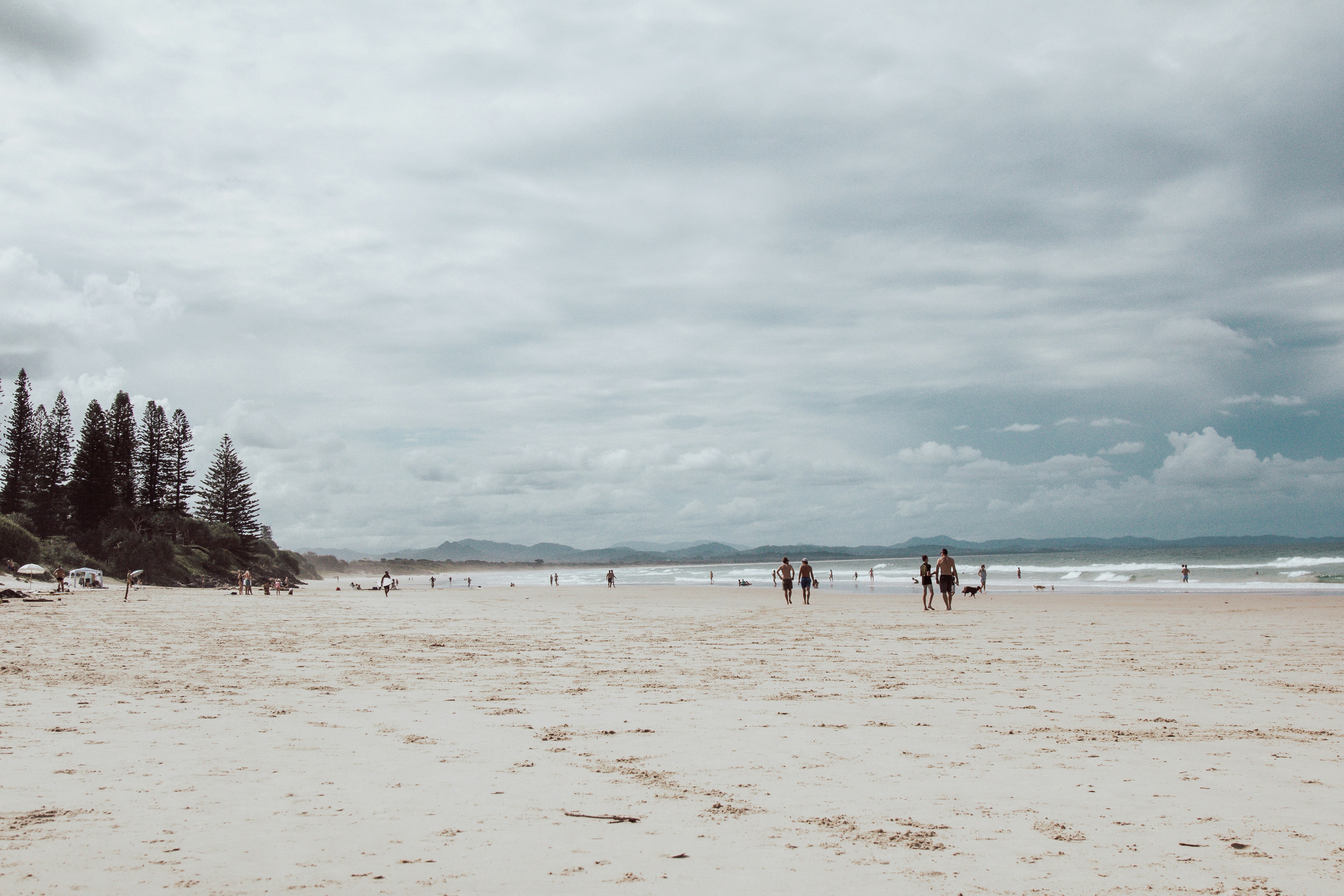 People relaxing and walking on the beach, under cloudy sky
