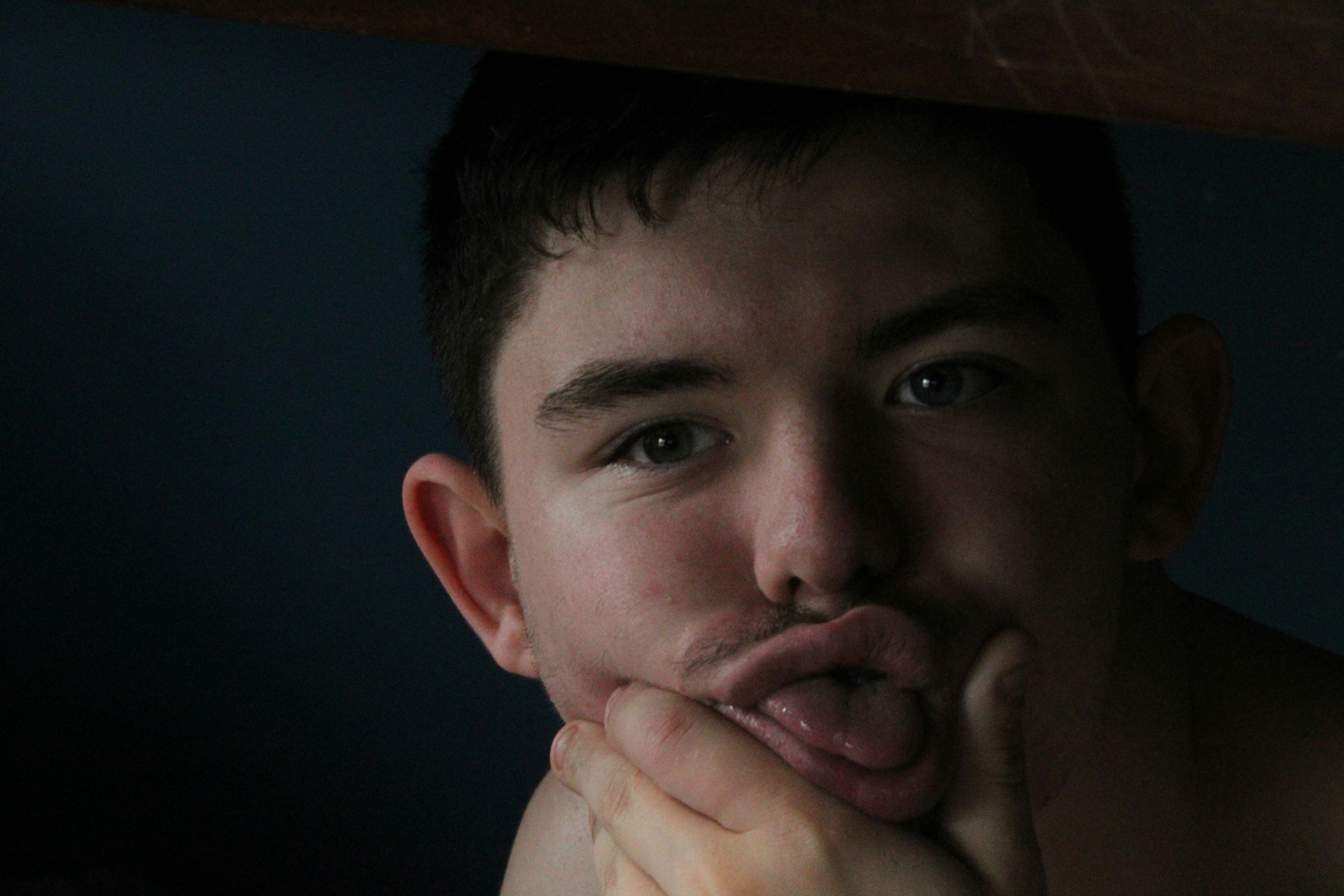 a-young-man-sticking-his-tongue-out-under-a-table-photo-free-human