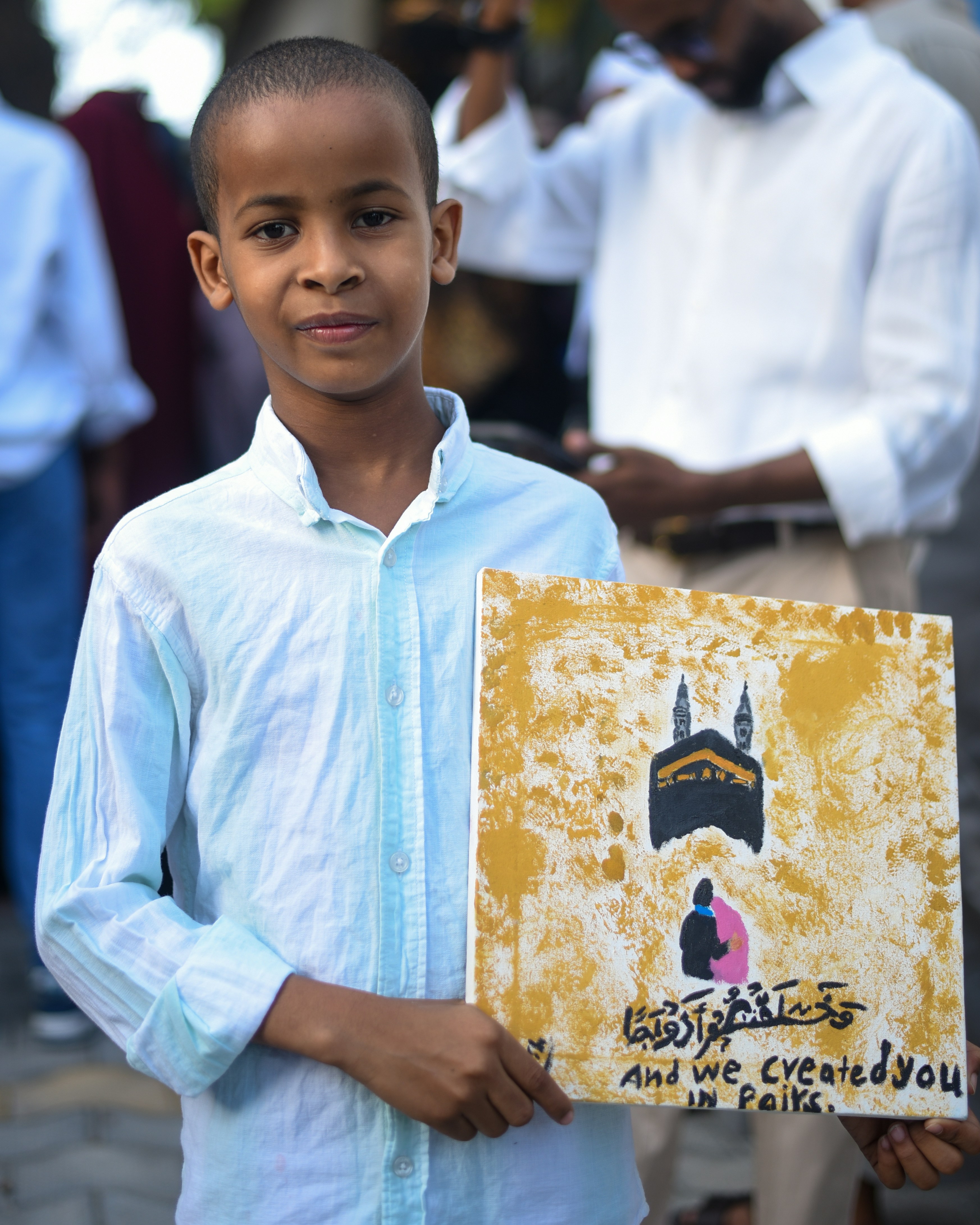 A young boy holding a sign in front of a group of people