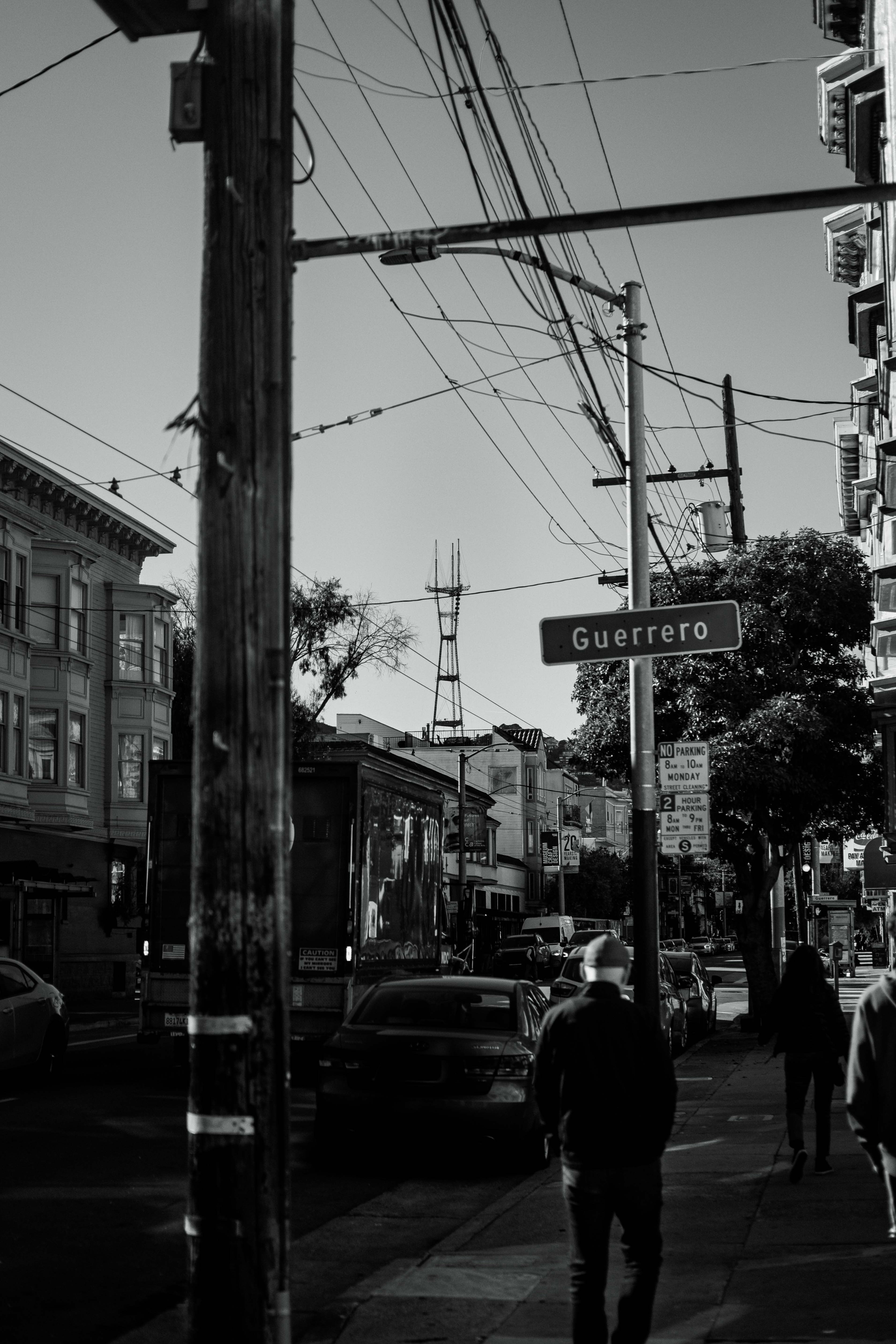 A group of people walking down a street next to tall buildings