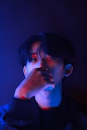 A man in a dark room holding his hand to his face