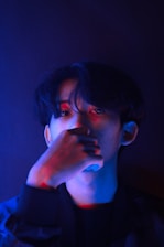 A man in a dark room holding his hand to his face