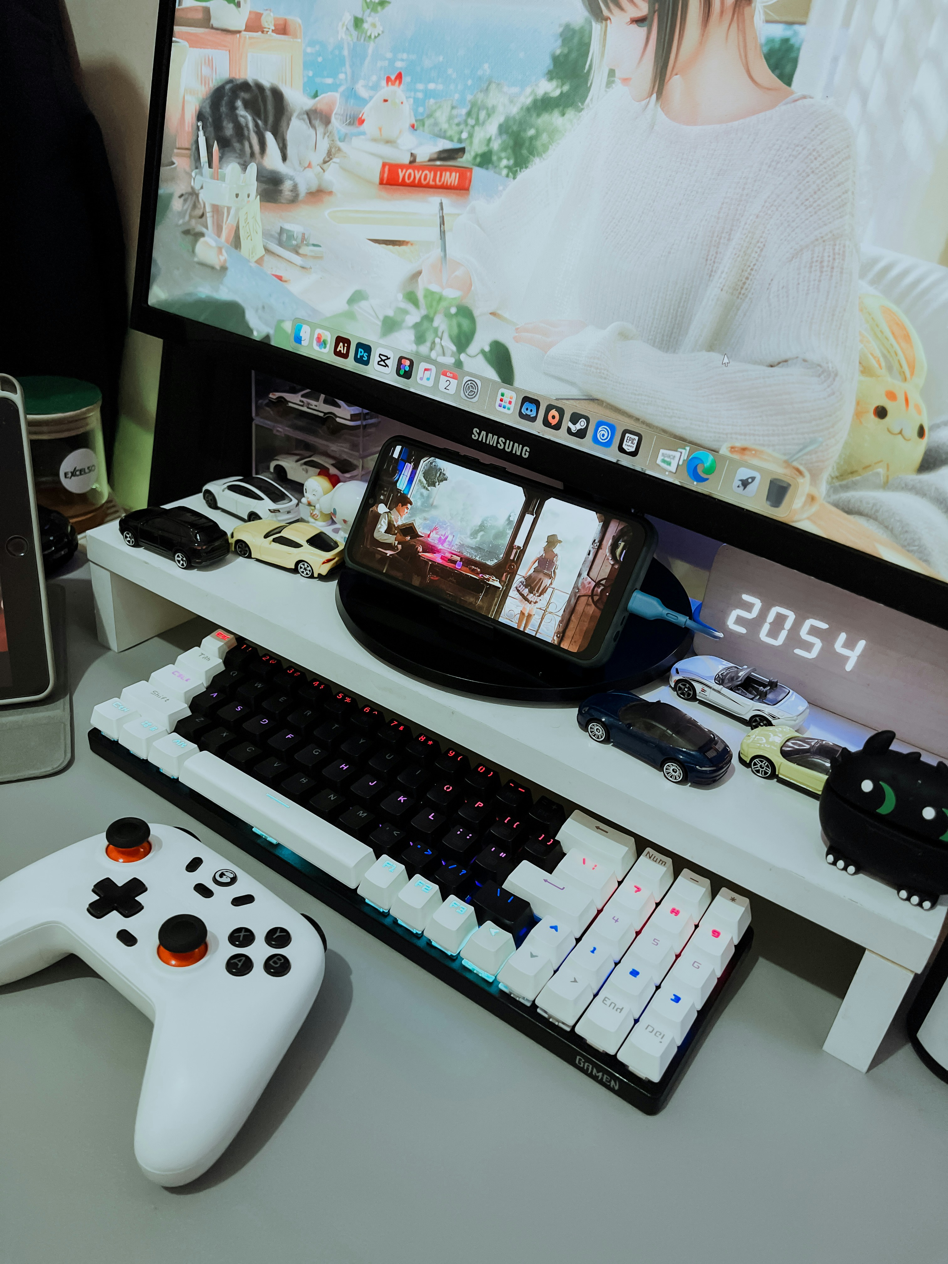 A desk with a computer, keyboard, and a video game controller