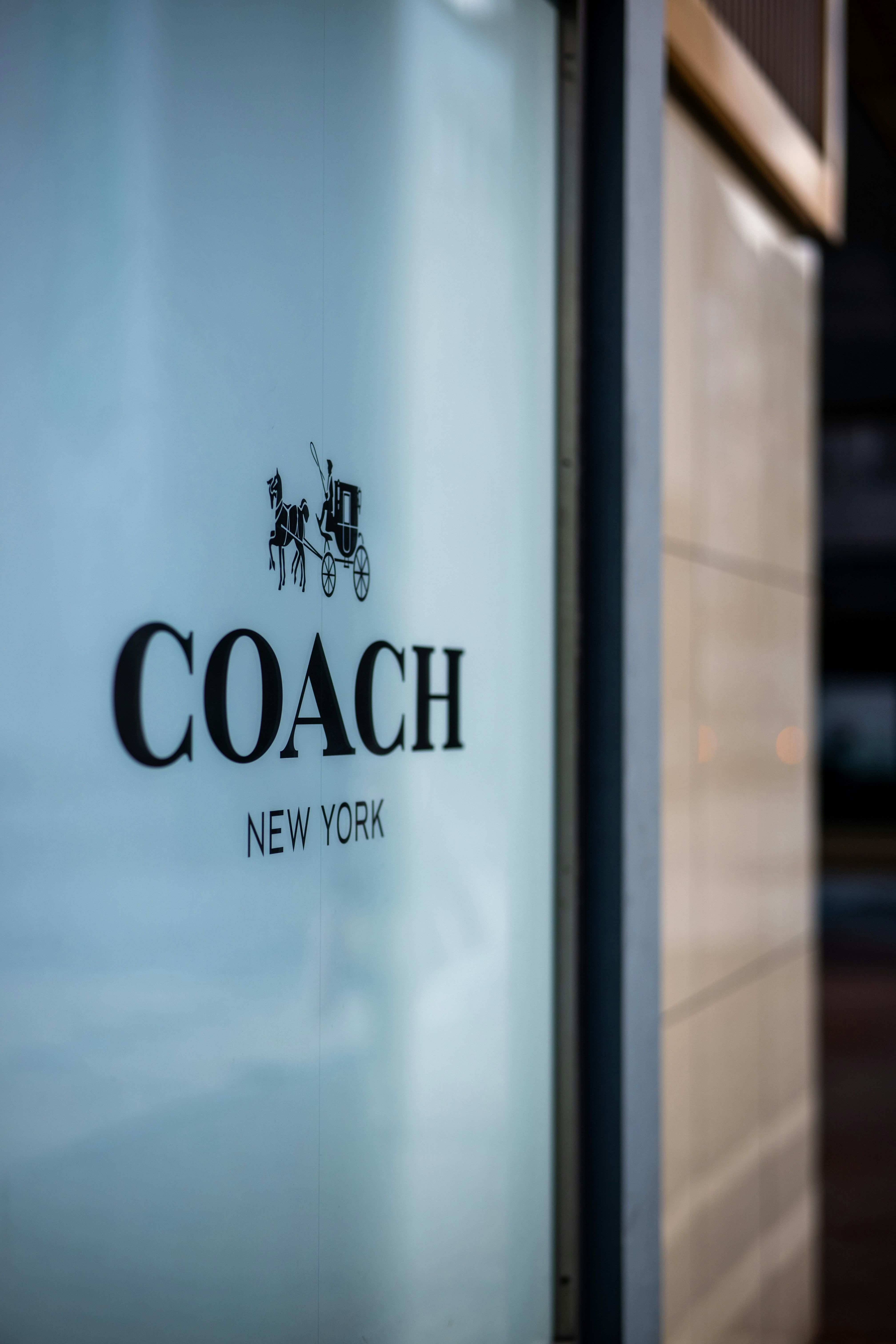 A close up of a coach logo on a glass door